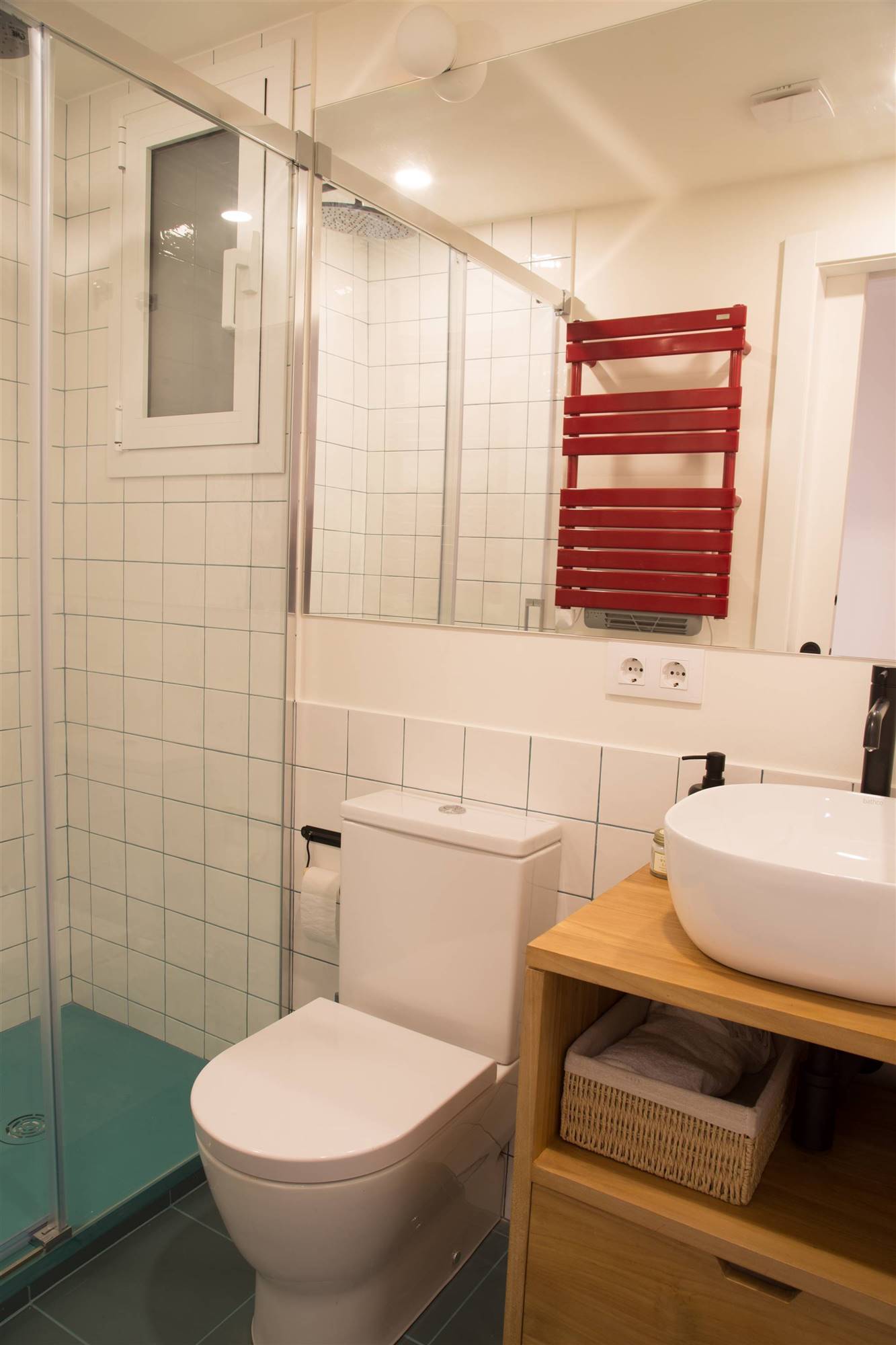 Un baño pequeño con toques de color y una pequeña cabina de ducha.