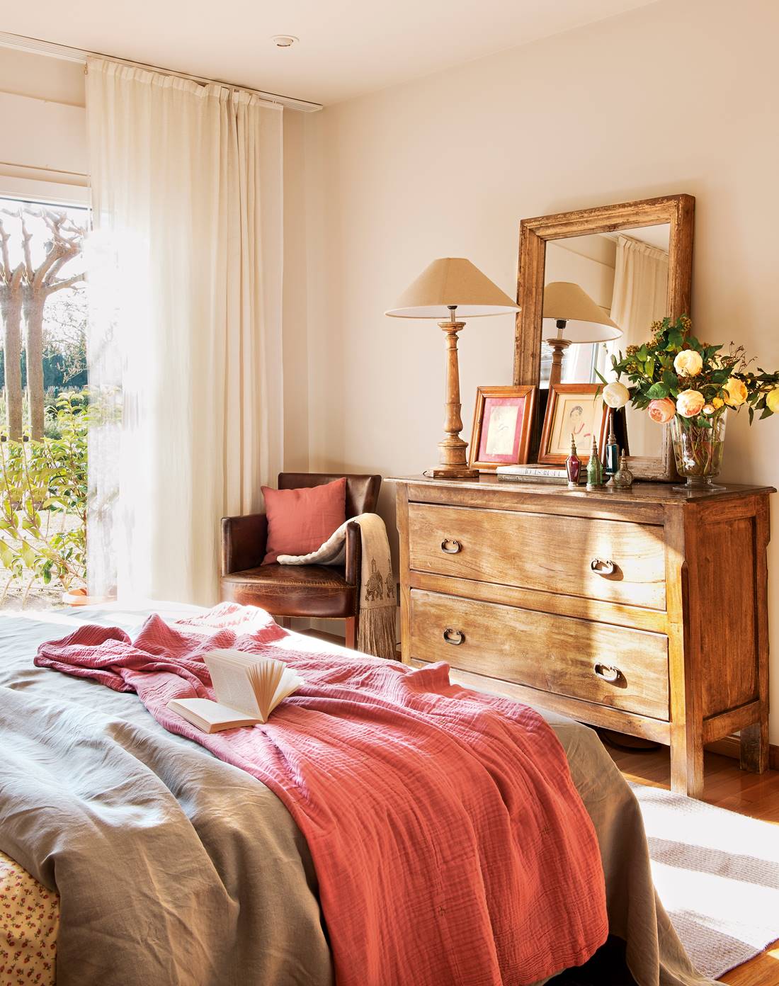 Dormitorio con cómoda de madera y butaca de cuero.