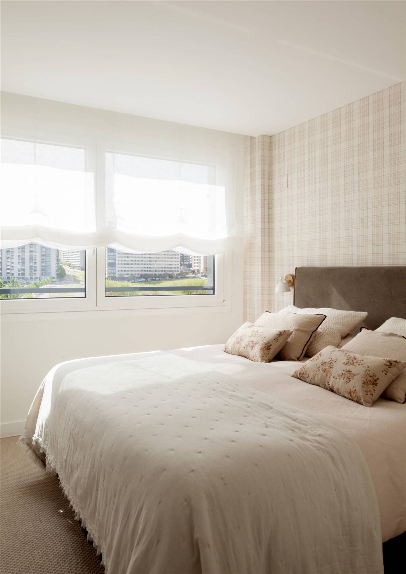 Dormitorio principal con cabecero tapizado y papel pintado.