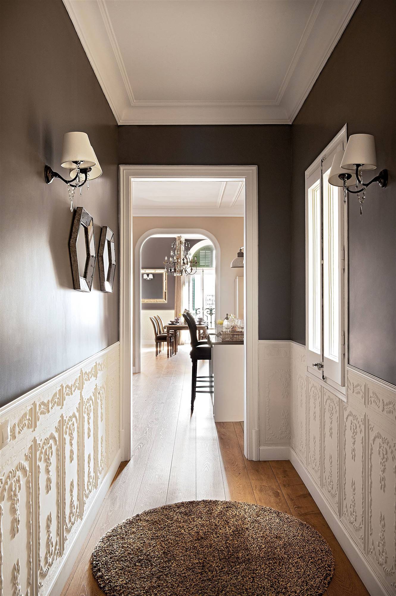 Pasillo con apliques de pared clásicos y arrimadero con molduras decorativas.