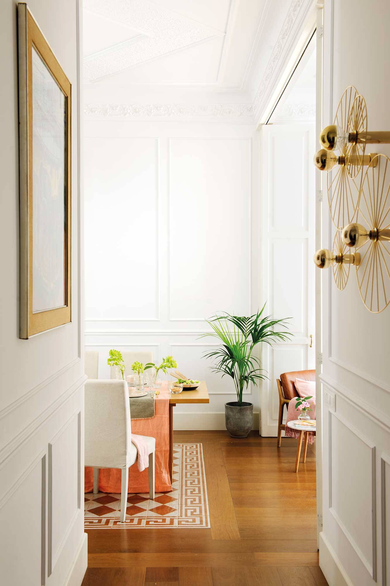 Pasillo con apliques dorados metálicos y molduras decorativas en la pared en color blanco.