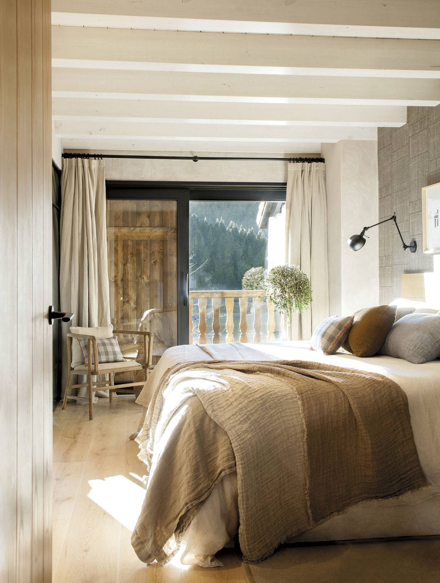 Dormitorio en tonos tierra con la pared del cabecero con papel pintado efecto textil. 