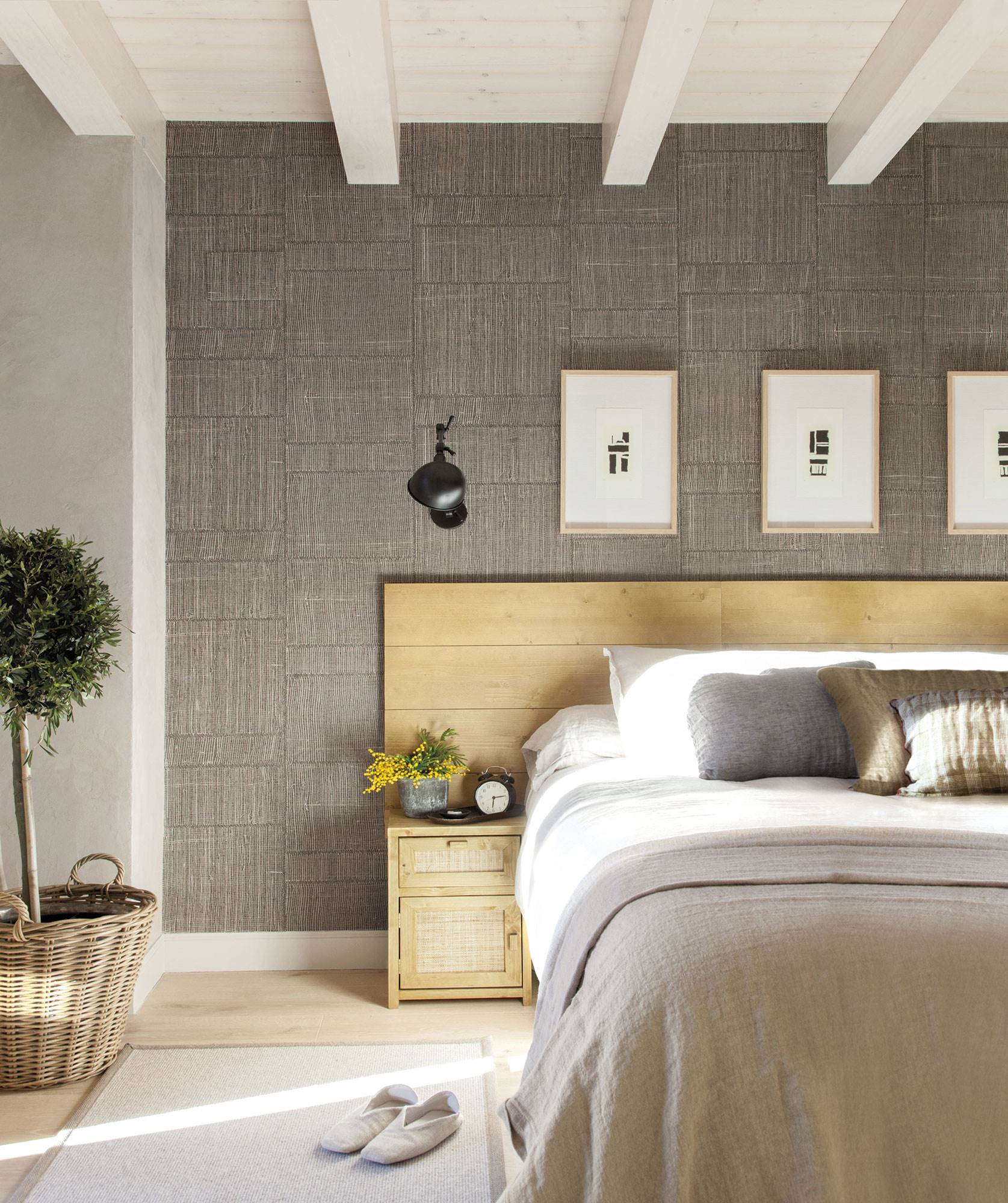 Dormitorio con cabecero de madera y pared con papel pintado efecto textil. 