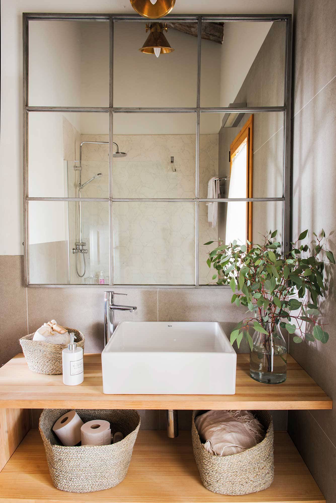 Baño con mueble de madera y espejo tipo ventana. 