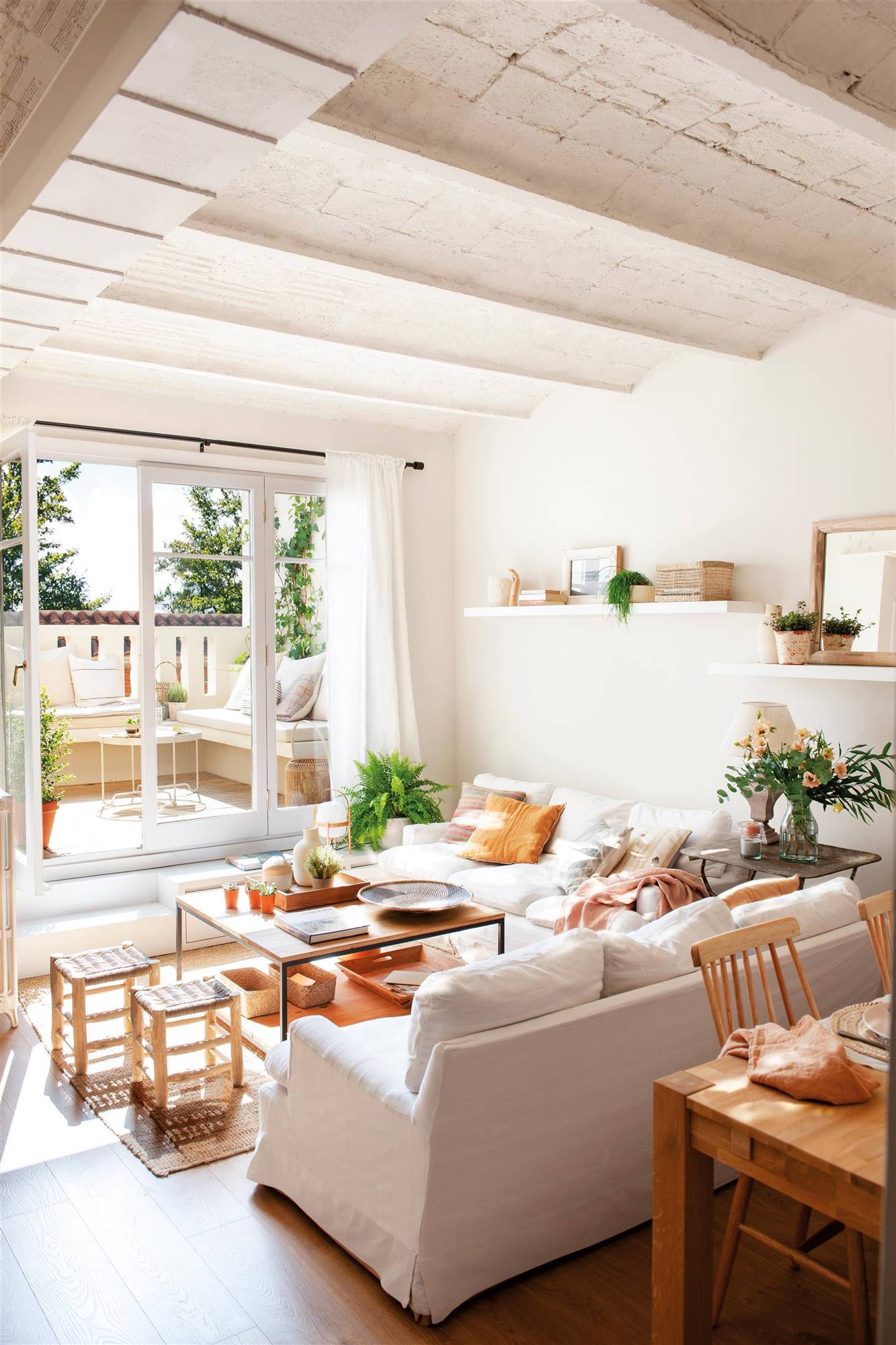 Salón con sofás y paredes blancas y muebles de madera. 