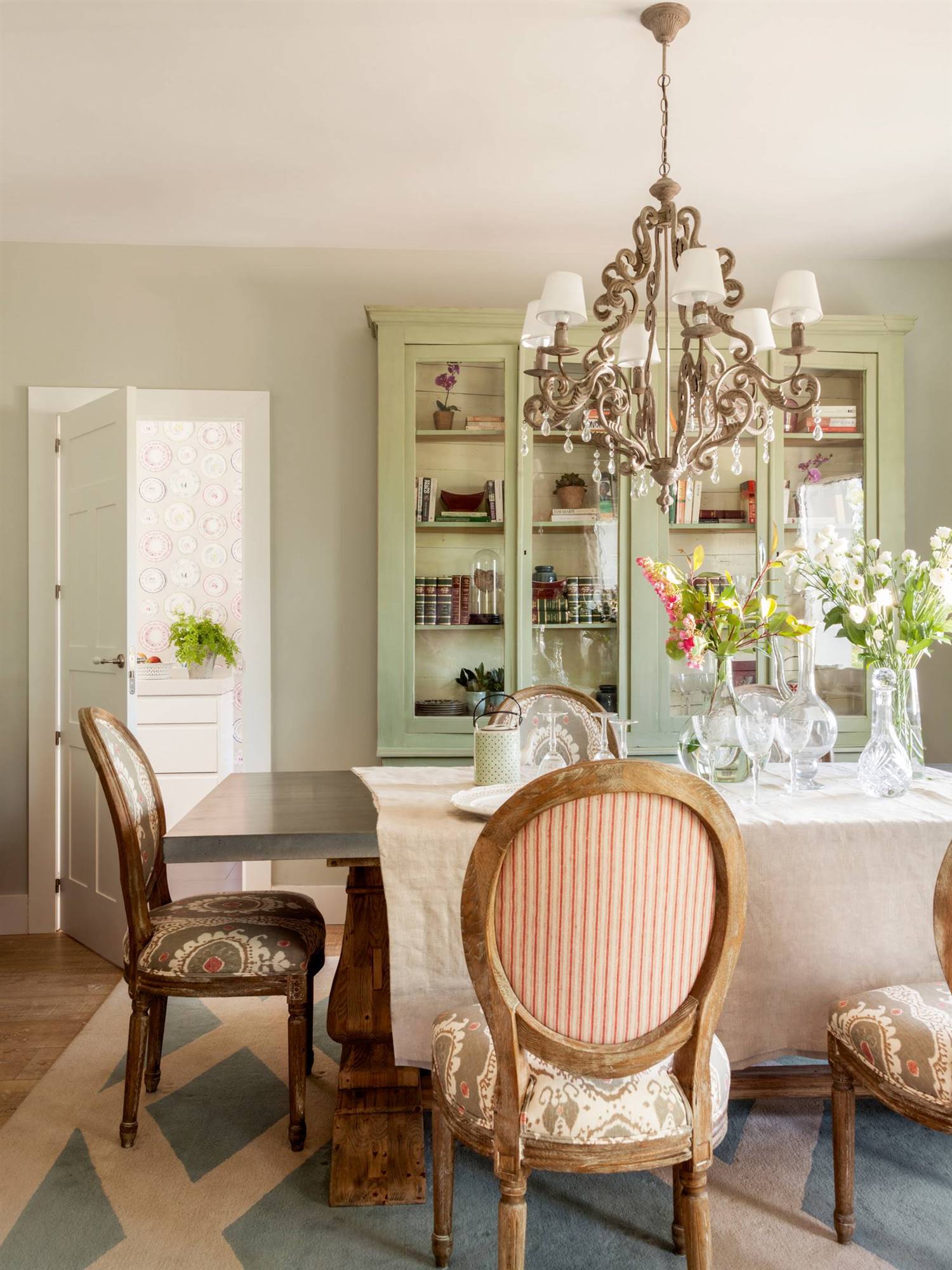 Comedor clásico con mesa y sillas de madera y vitrina de color verde. 
