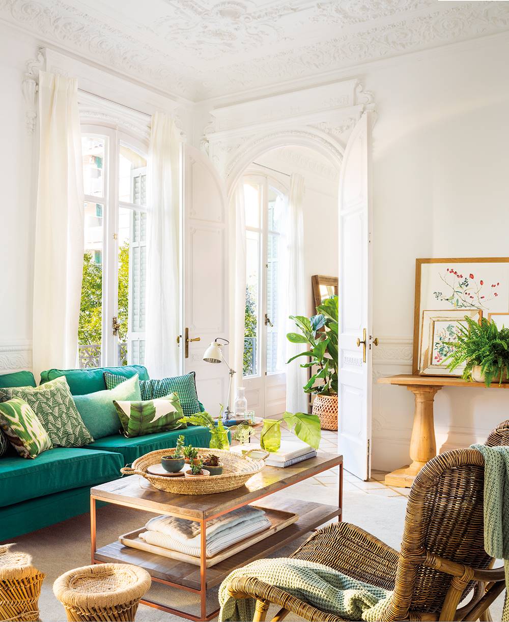 Salón con sofá verde y cojines de varios tonos de verde. 