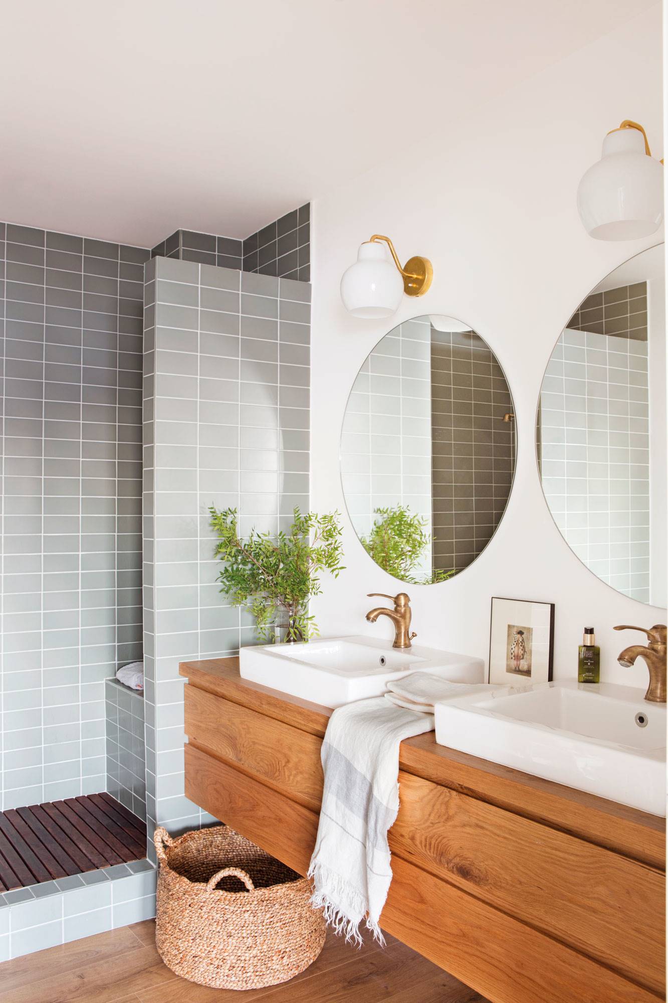 Baño con ducha con azulejos, mueble sobrevolado de madera y lavabos sobrepuestos. 