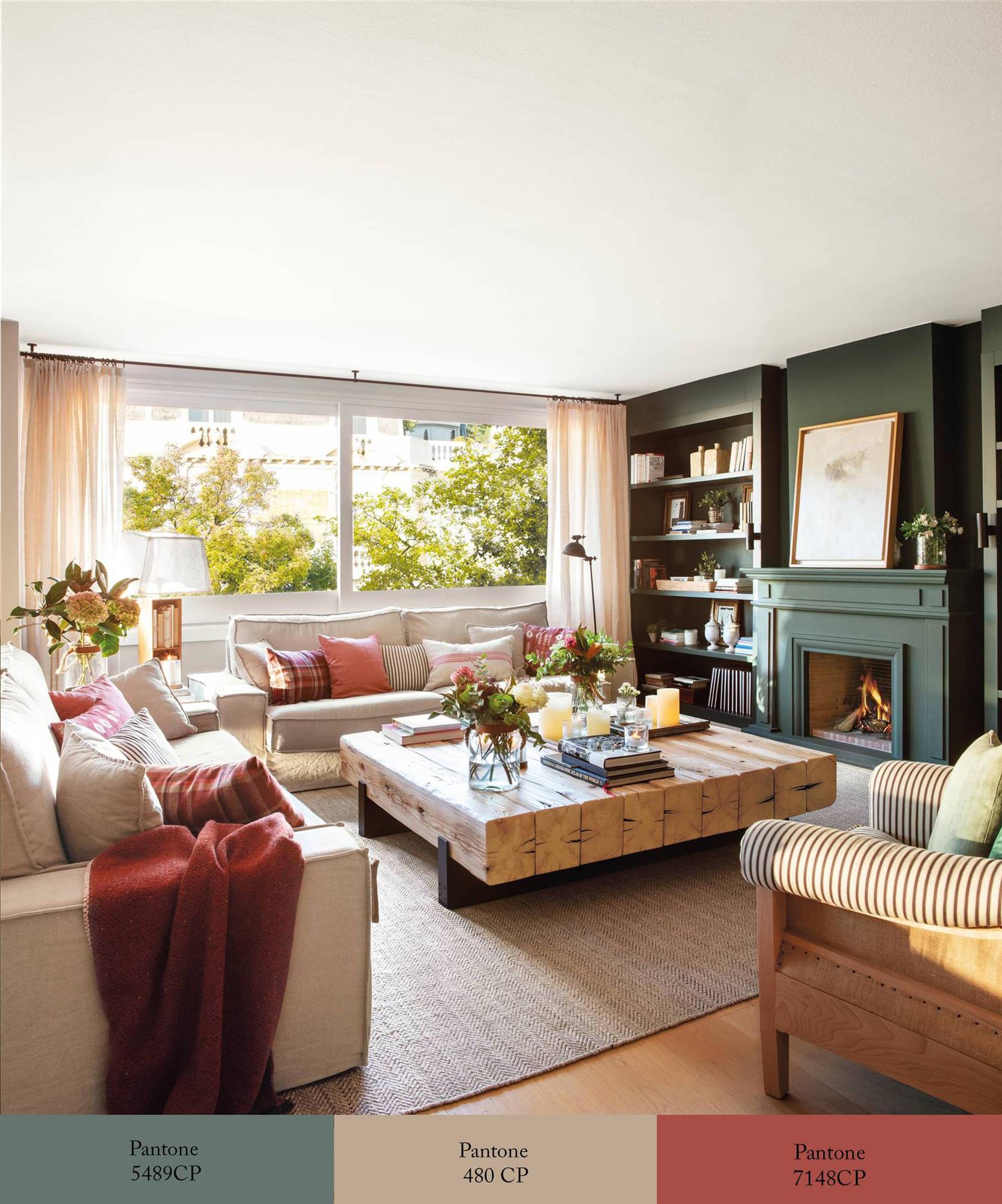 Salón con pared con chimenea pintada de verdigrís, sofás color arena y textiles en caldero. 