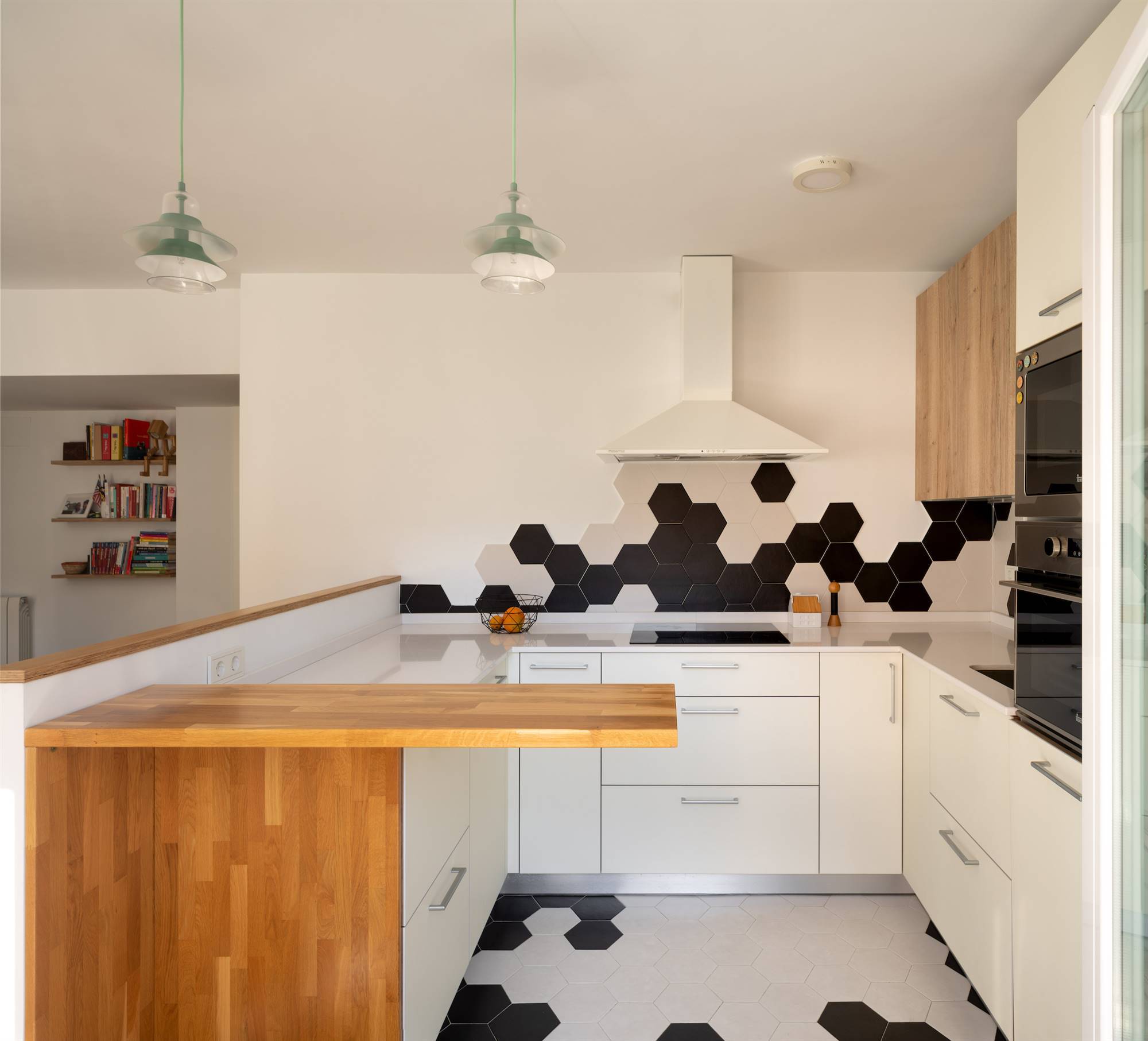 Una cocina moderna en forma de "U" con baldosas hexagonales en blanco y negro.