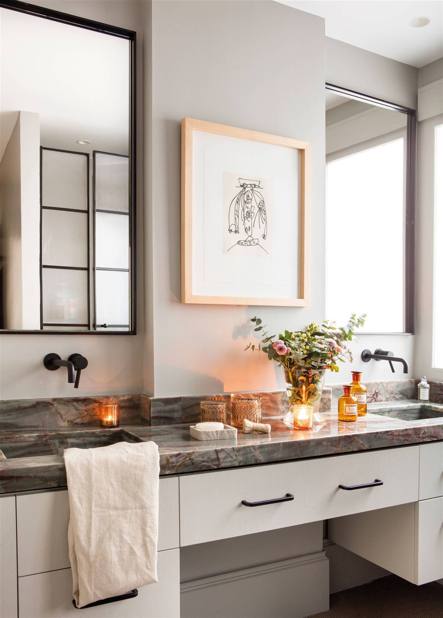 Baño con paredes y mueble de baño de color gris, encimera veteada y cuadro. 