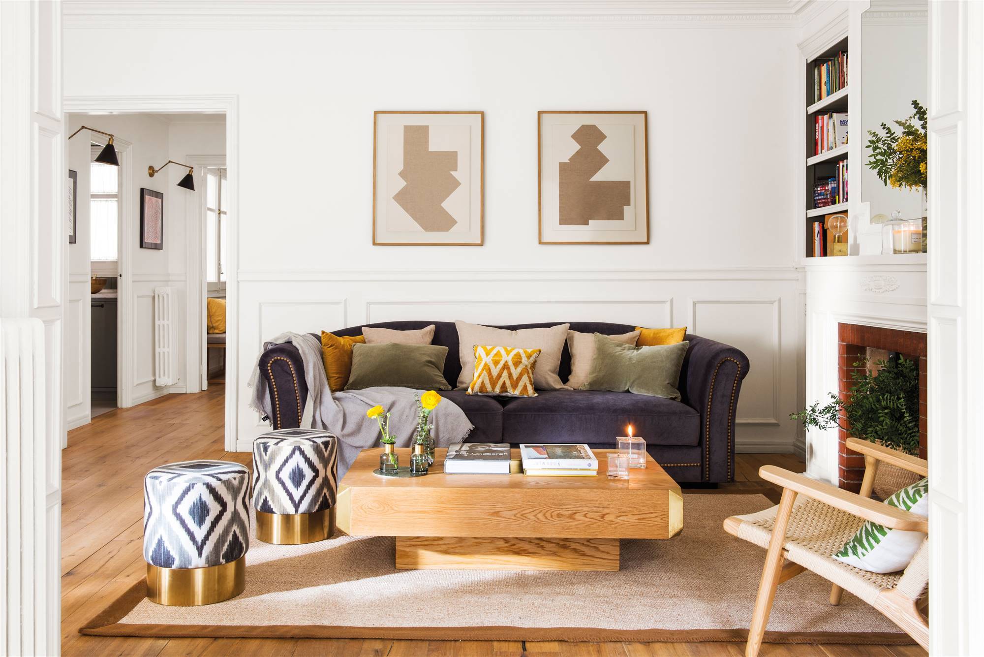 Salón con sofá azul, paredes blancas y detalles en dorado. 