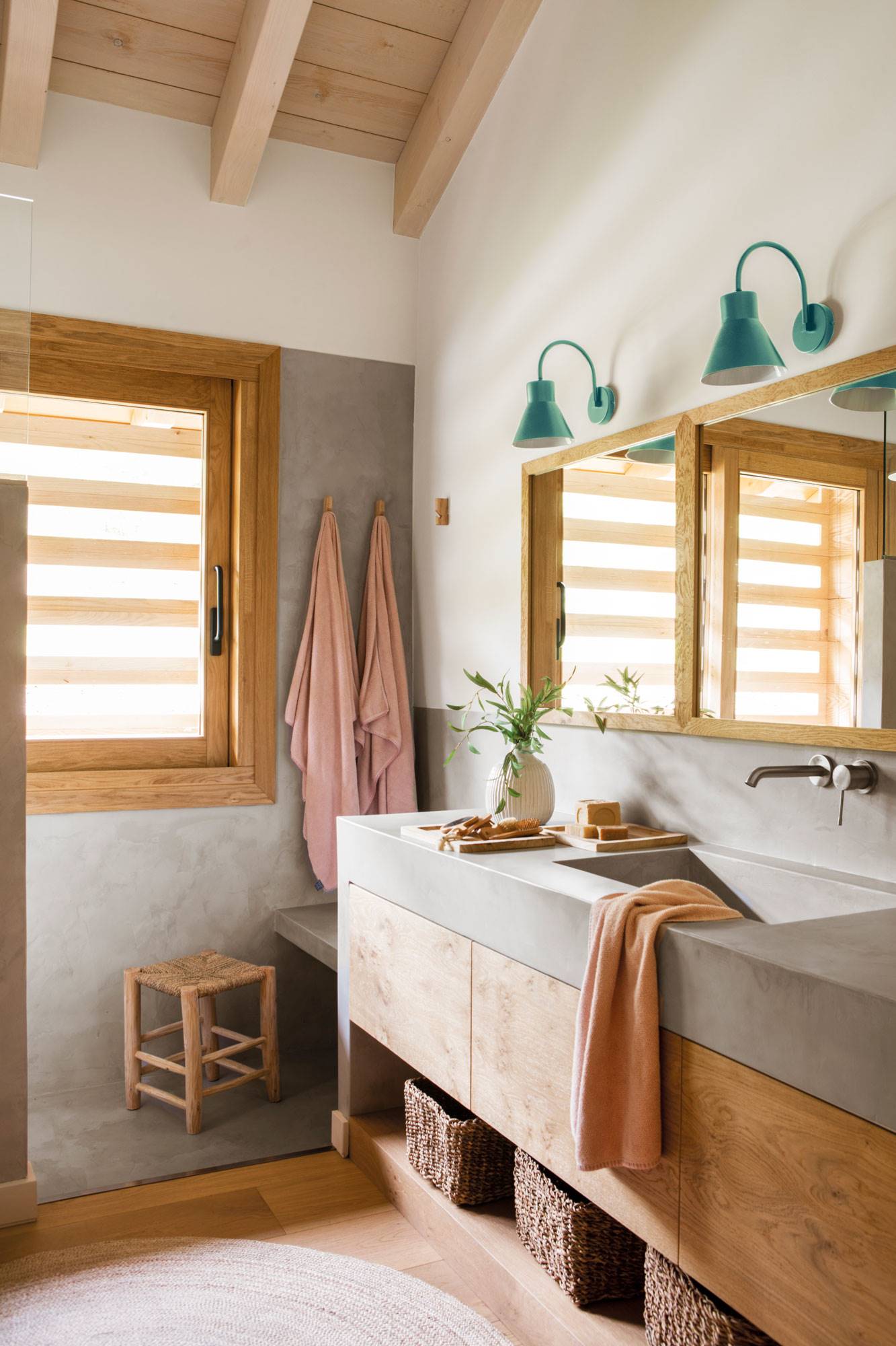 Baño con encimera y lavabo de microcemento, mueble de madera y alfombra de fibra natural.  