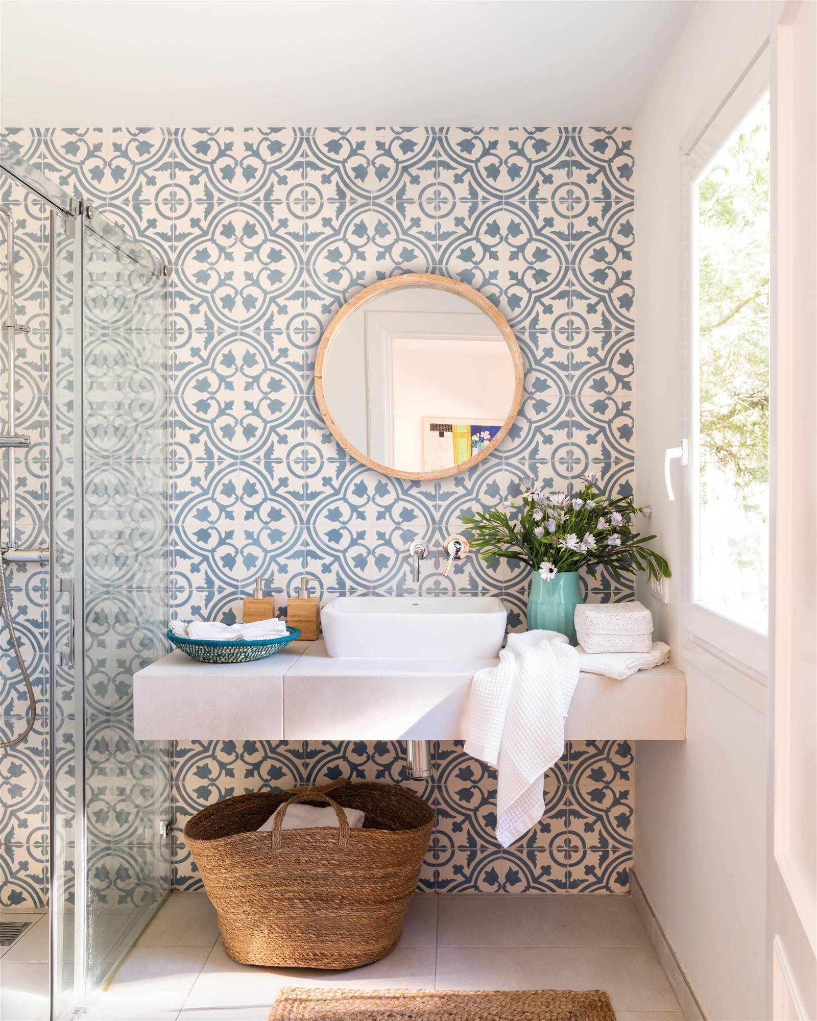 Baño con azulejos con acabado hidráulico y mueble de baño suspendido de color blanco. 