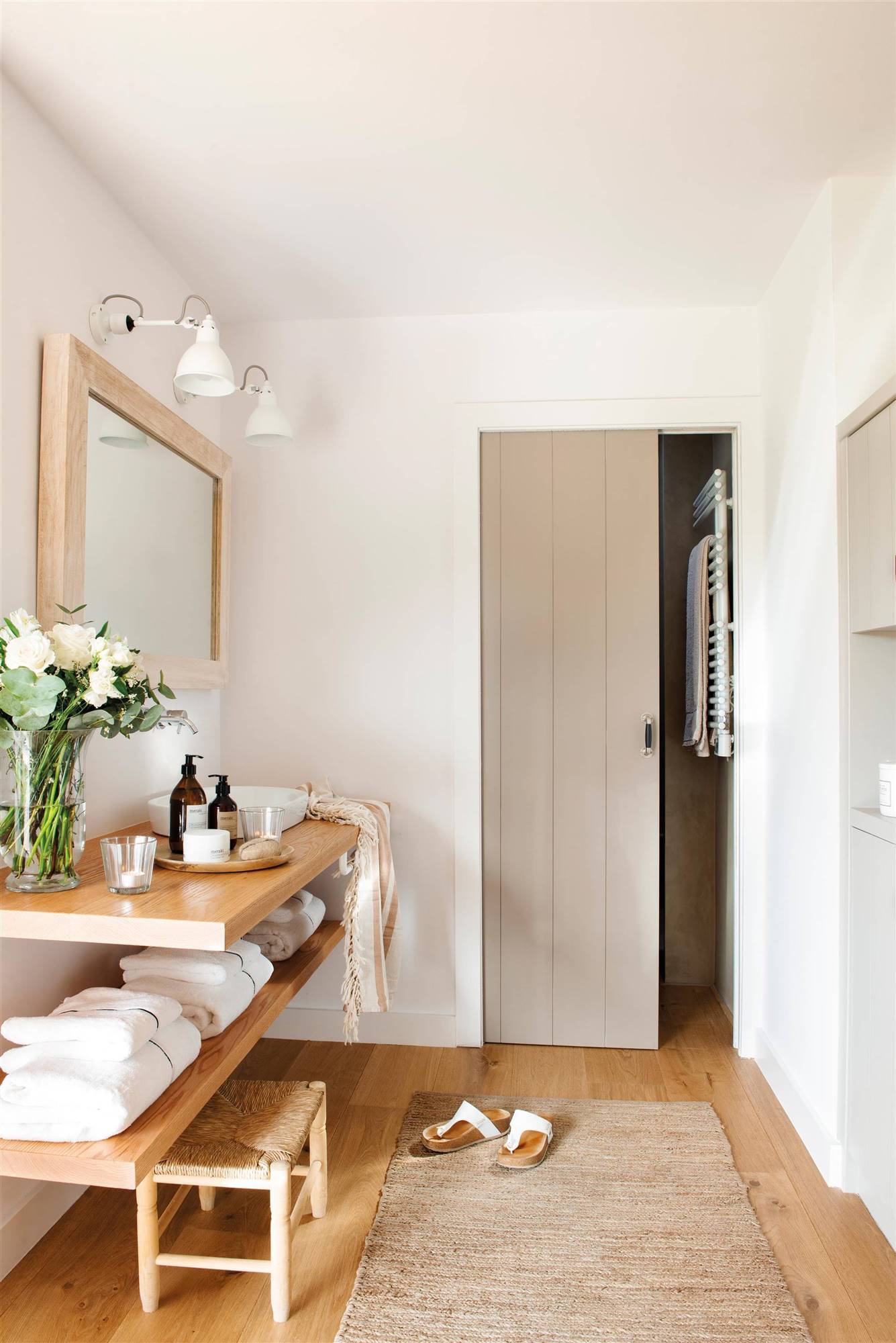 Baño con mueble de lavabo con balda de madera y radiador toallero en la pared. 