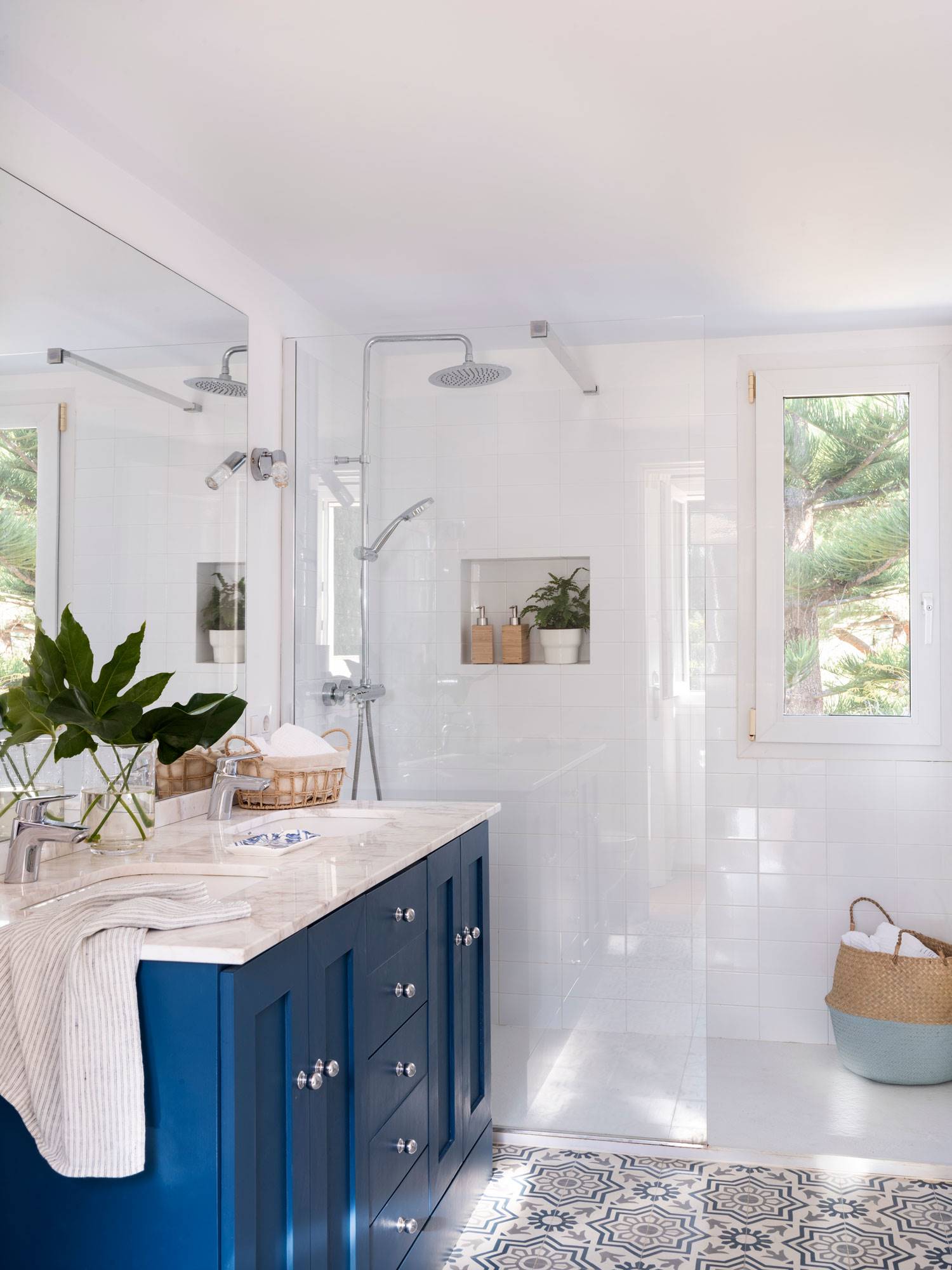 Baño clásico con mueble azul, encimera de mármol y mampara transparente. 