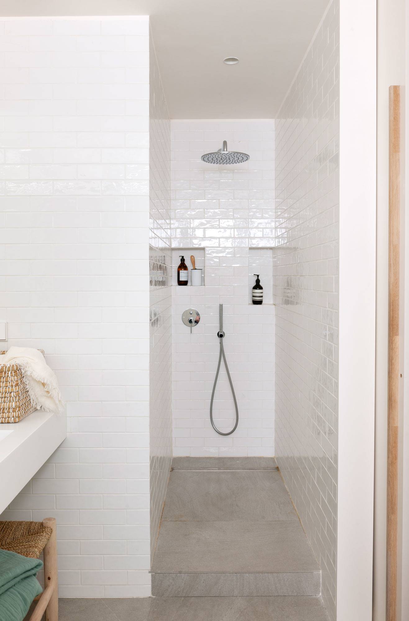 Zona de ducha revestida con azulejos de color blanco. 