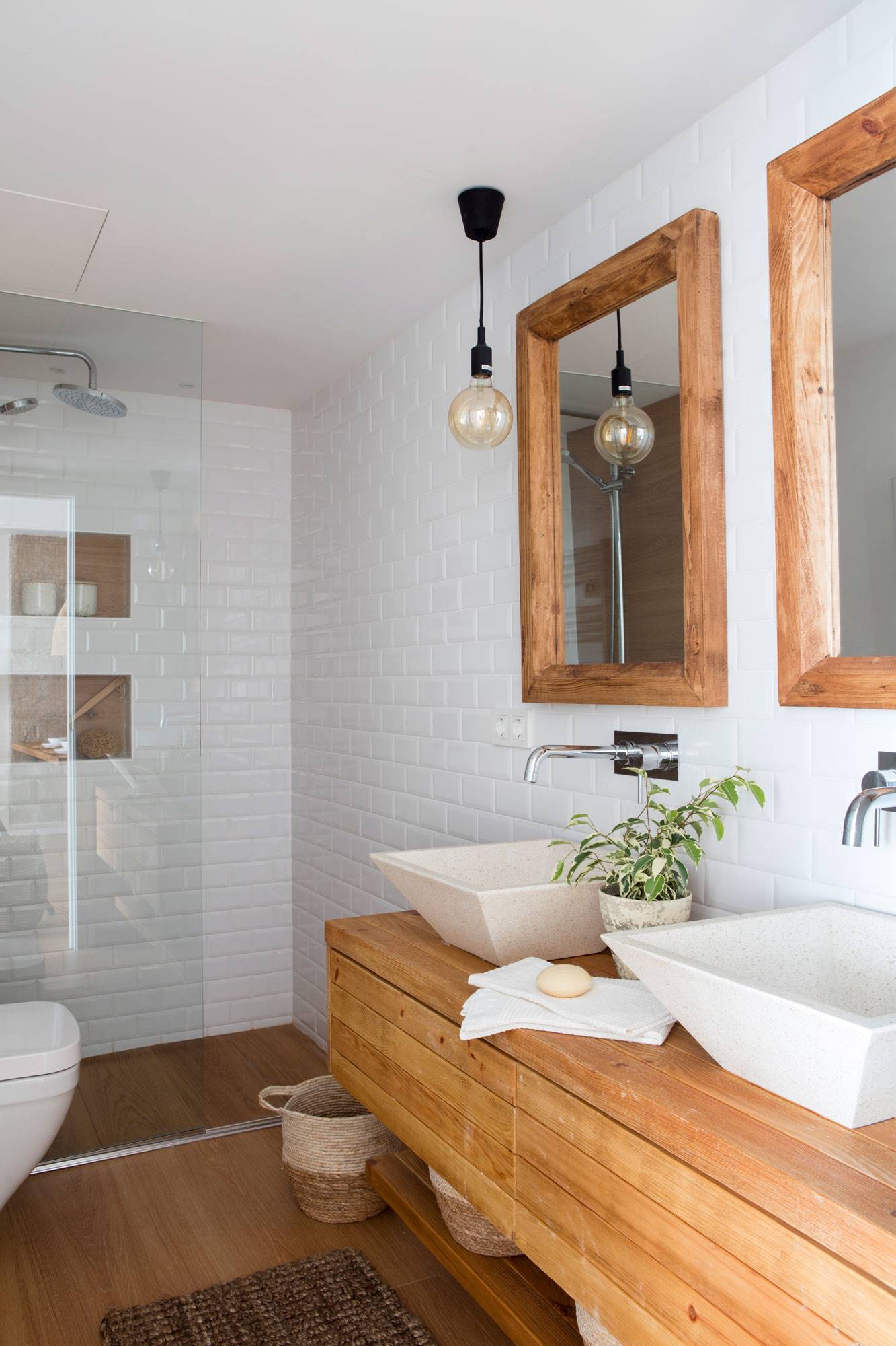 Baño con ducha y mueble de madera con doble lavabo sobre encimera. 