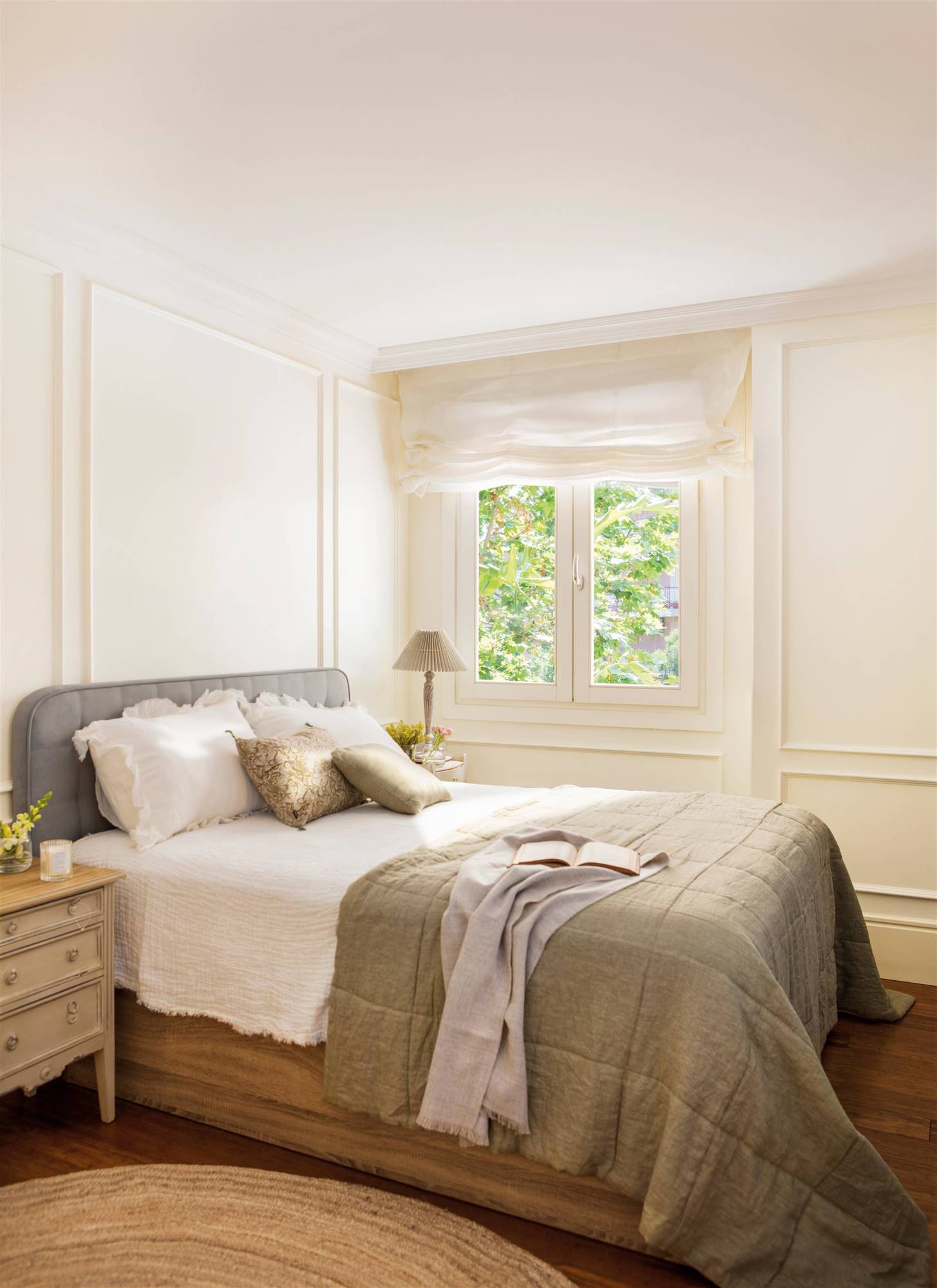 Dormitorio con la pared blanca con molduras y cabecero en gris. 
