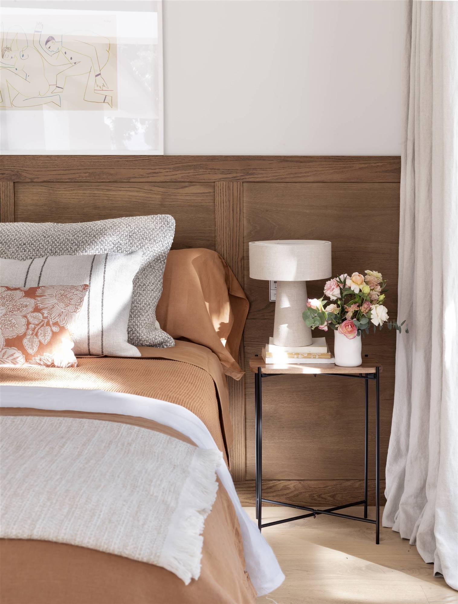 Dormitorio con cabecero de madera de pared a pared y ropa de cama color blanca y teja. 