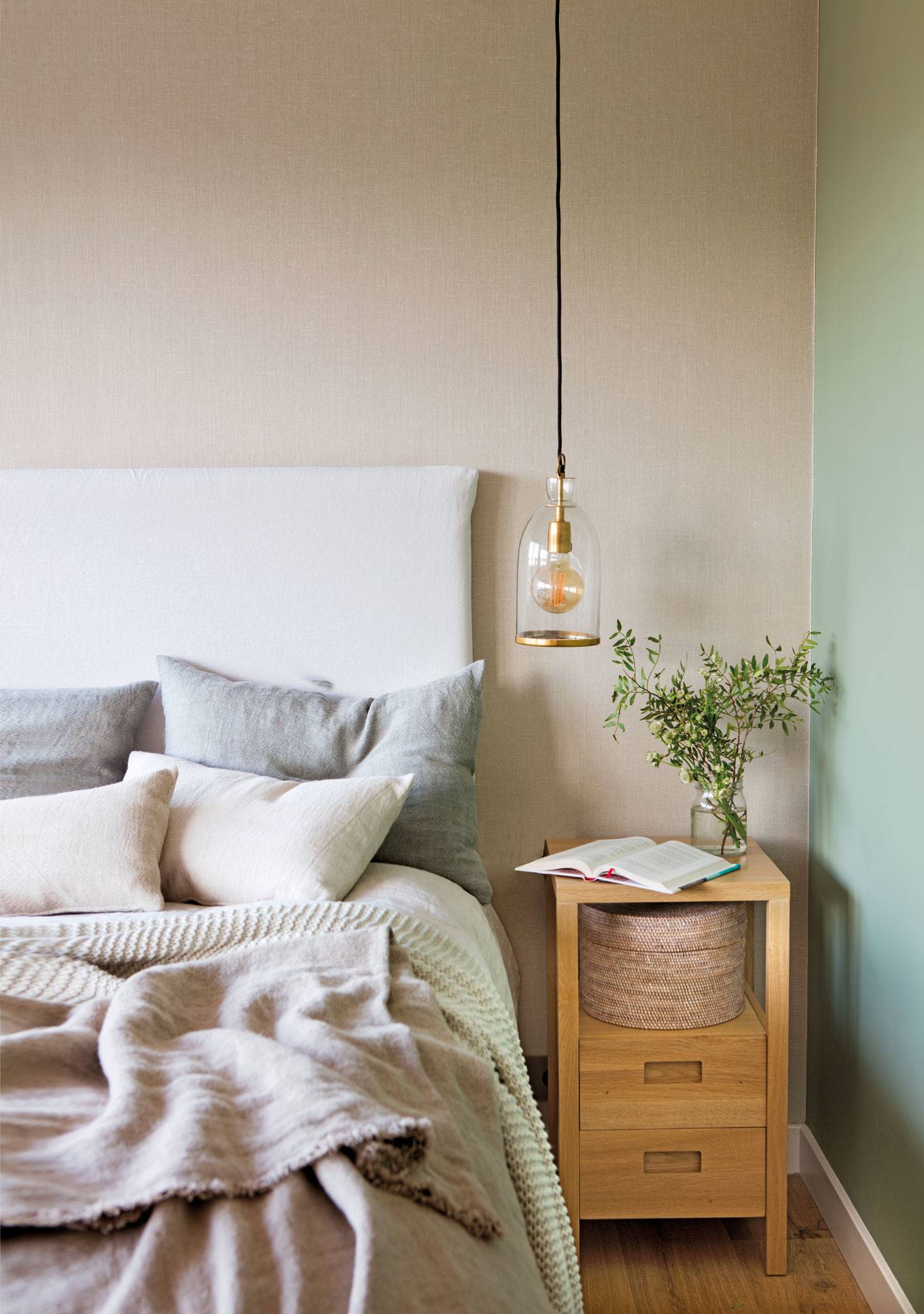 Dormitorio pintado en dos colores con lámpara colgante sobre la mesita de noche. 