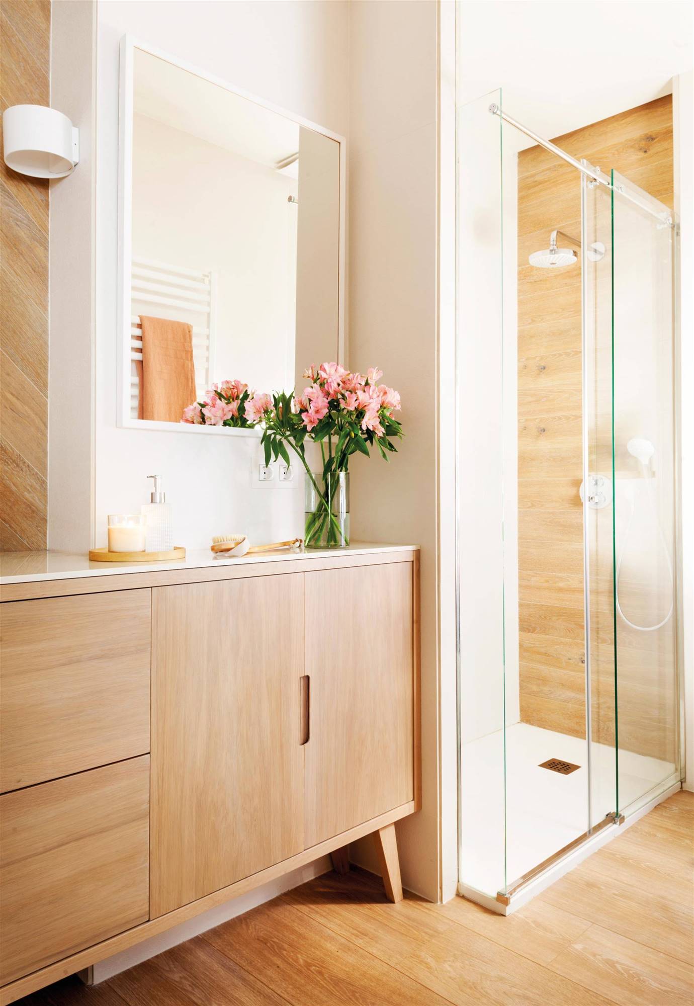 Baño con mueble nórdico de madera y ducha al fondo. 