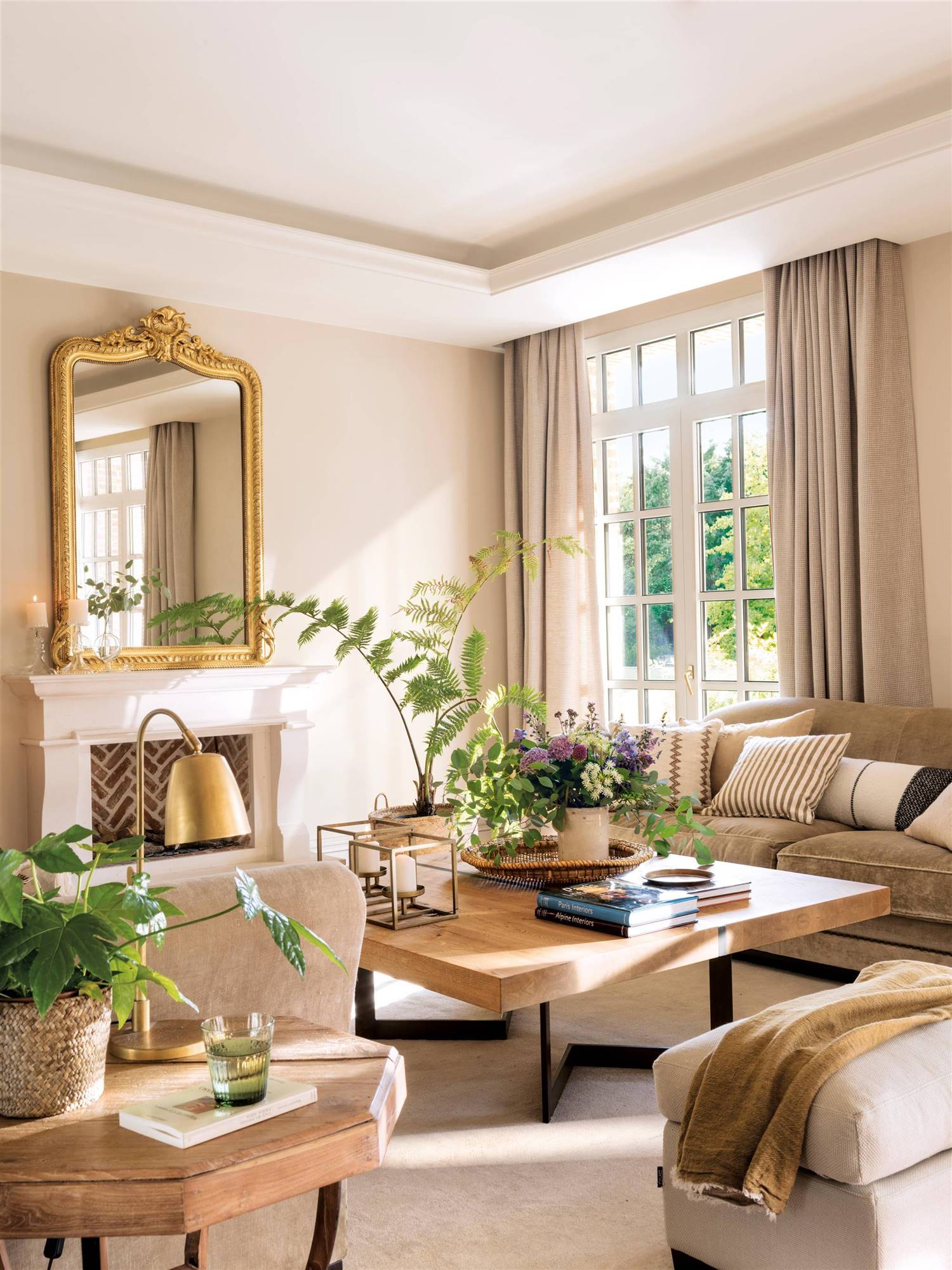 Salón con sofás de terciopelo y espejo dorado sobre la chimenea