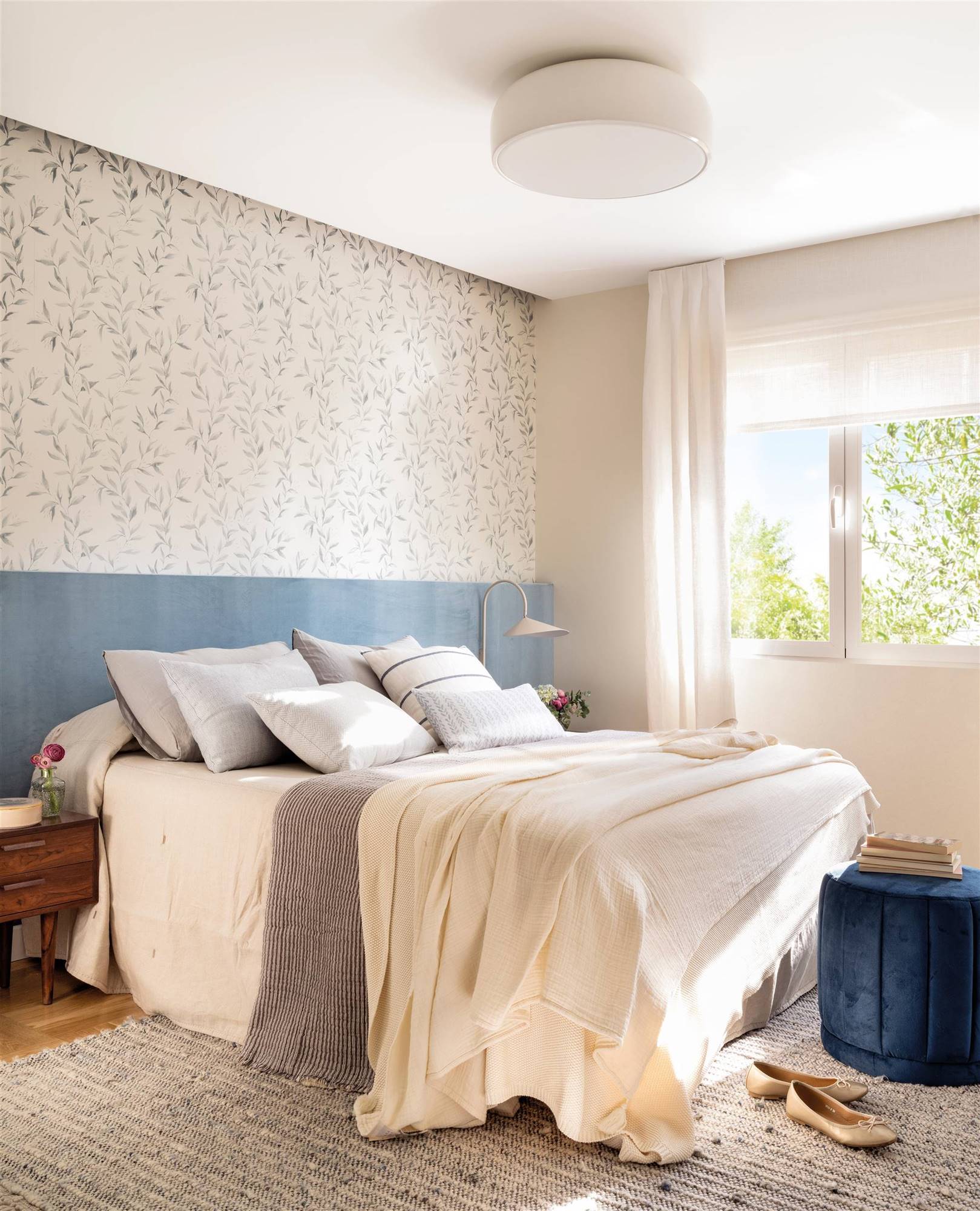 Dormitorio con cabecero de lino azul de pared a pared, revestida de papel pintado.