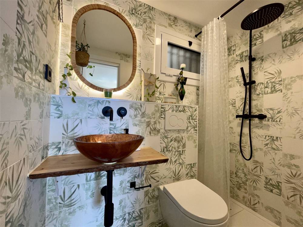 Baño de invitados con azulejos en blanco mate y otros con motivos florales de la lectora Gemma Morelló.