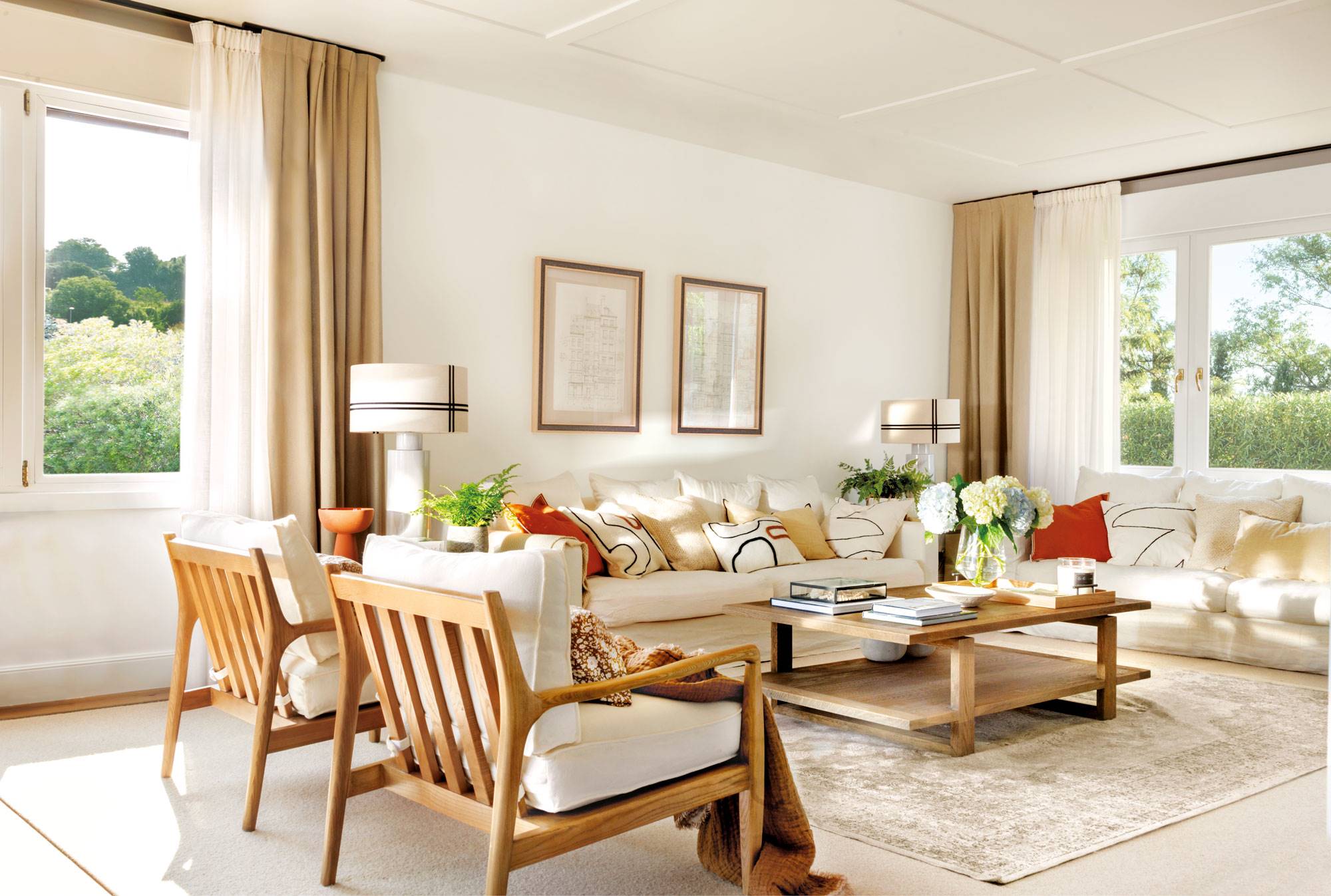 Salón con butacas con resutura de madera, sofás blancos y cojines de colores. 