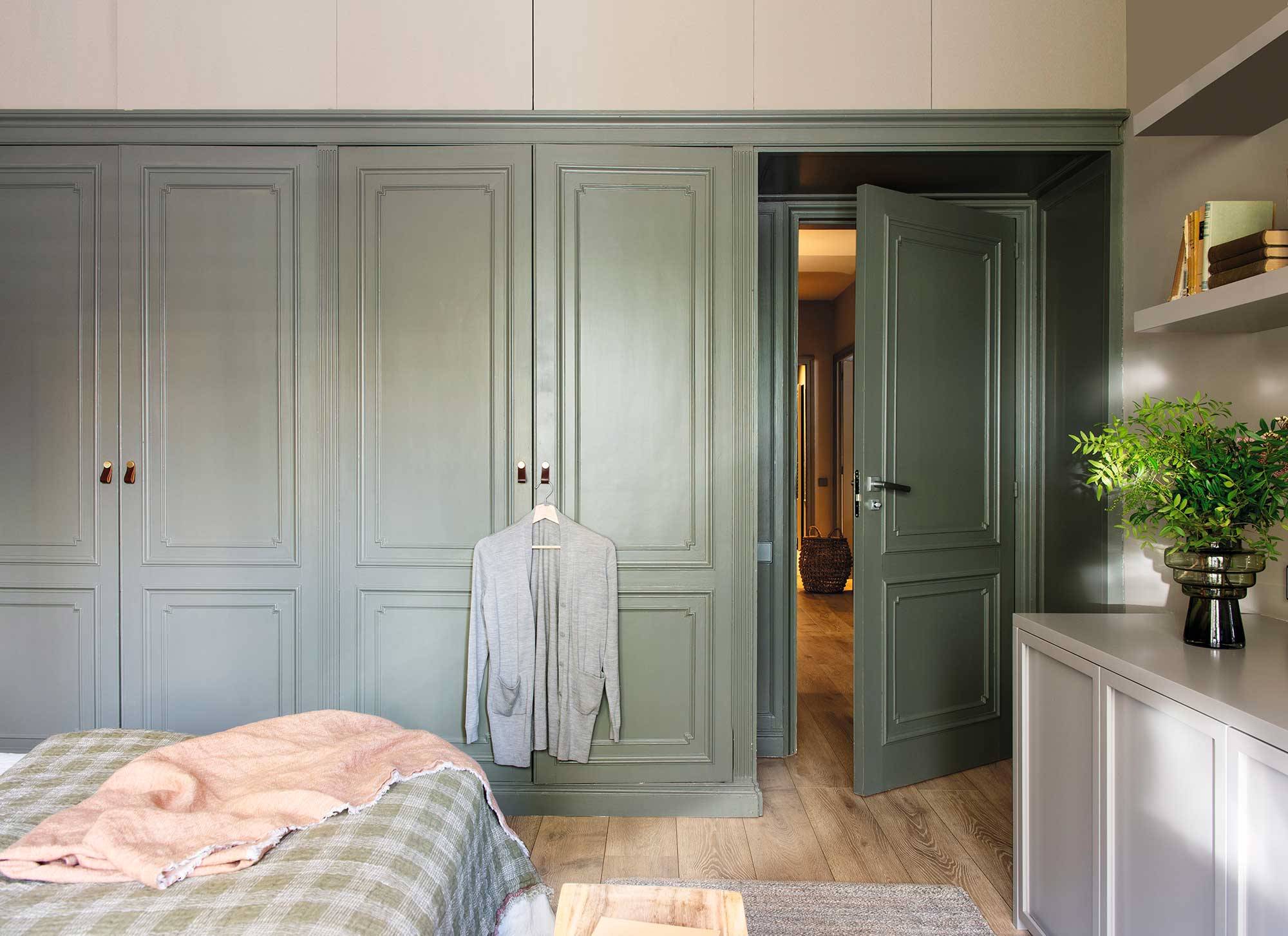Dormitorio con armarios verdes con molduras. 