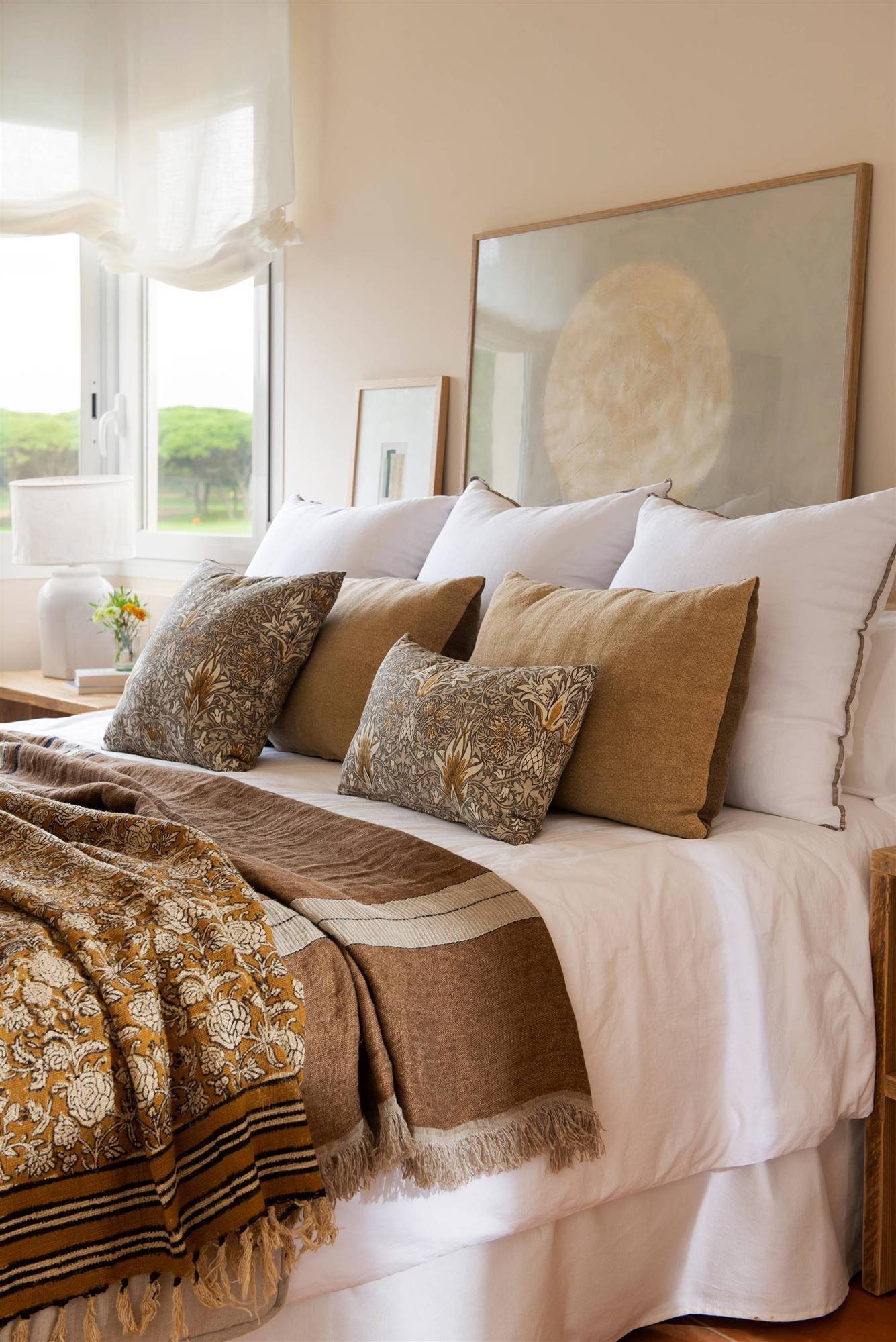 Dormitorio con cojines blancos de lino y estampados.