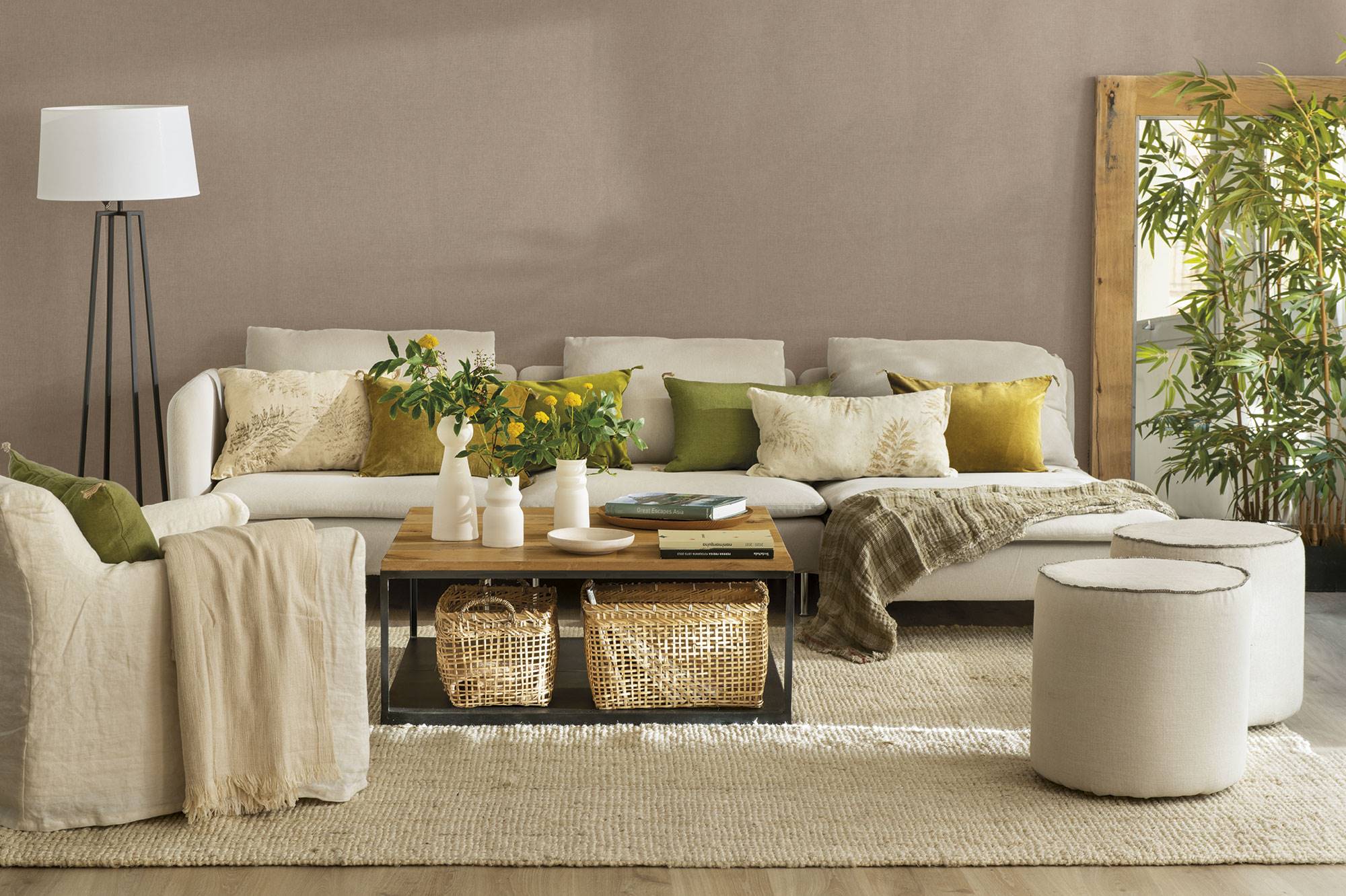 Salón con pared marrón, sofá, butaca y pufs de color blanco, mesa de centro de madera y hierro y alfombra de fibras.
