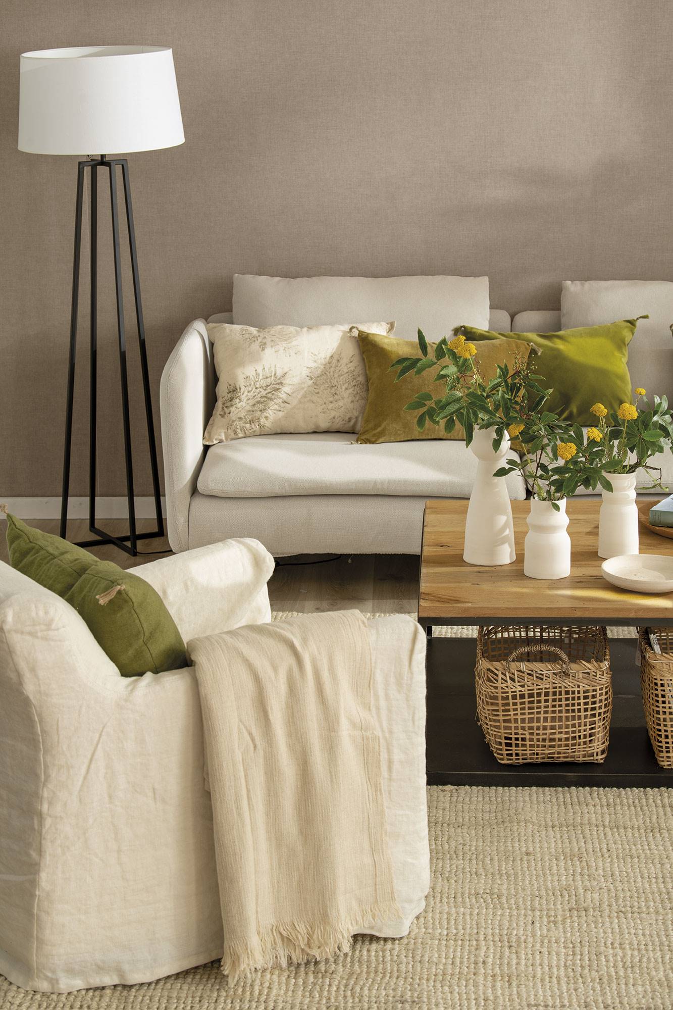Salón con pared marrón, sofá y butaca de color blanco, mesa de centro de madera y hierro y alfombra de fibras.