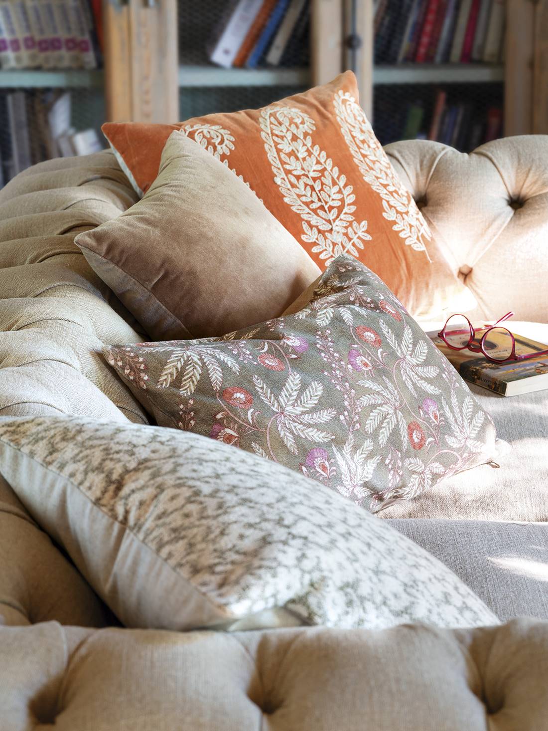Sofá con cojines de estampado floral, de terciopelo y colores cálidos otoñales.