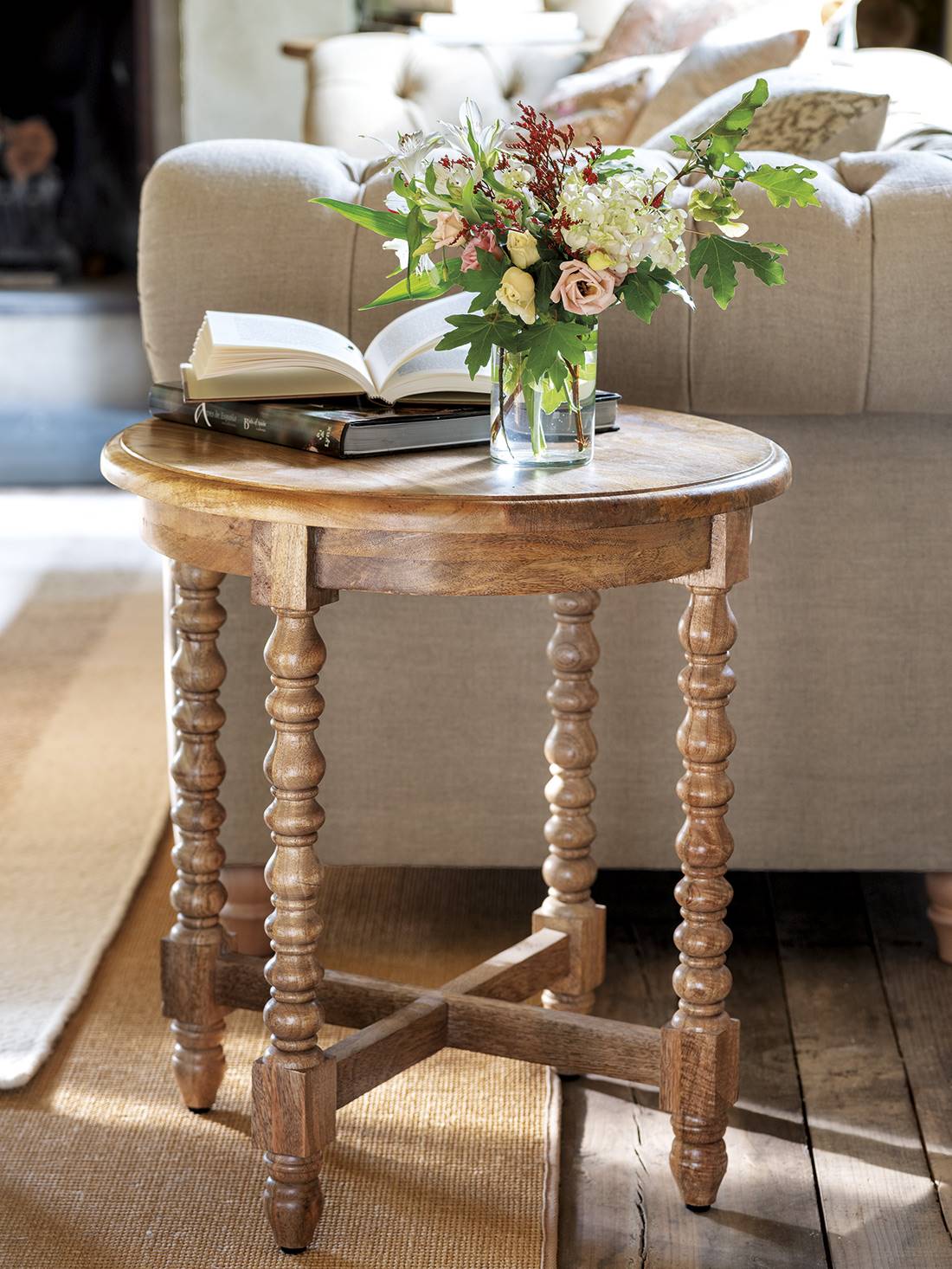 Mesa auxiliar de madera con las patas torneadas y jarrón con flores.