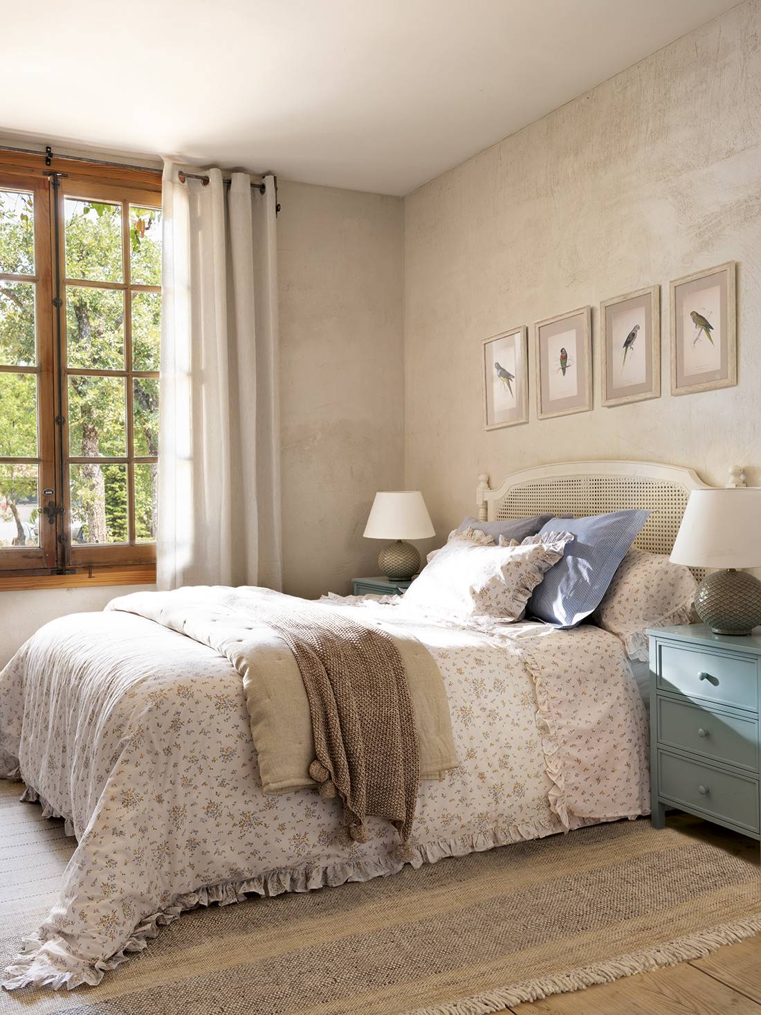  Dormitorio con cabecero blanco con rejilla, ropa de cama de flores, muebles decapados y volantes y pompones.