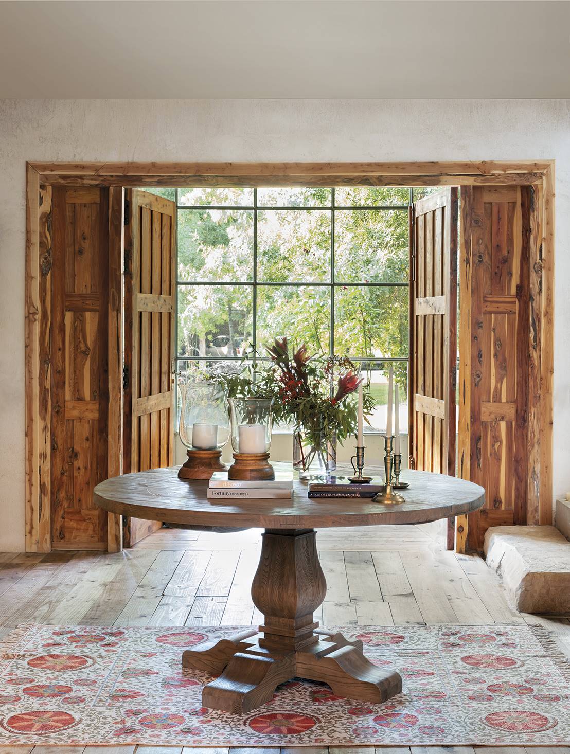 Un recibidor cálido decorado con una mesa redonda de madera y una alfombra clásica.