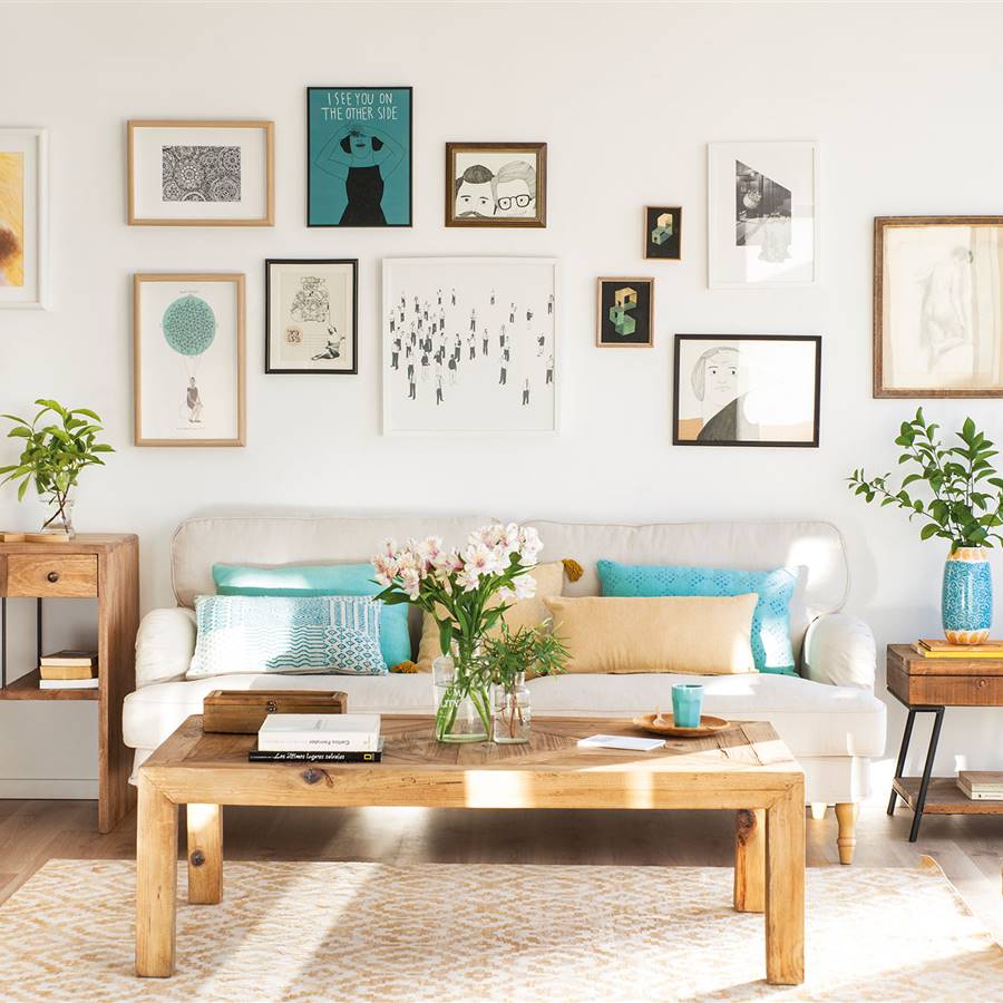 Salón con pared del sofá con composición de cuadros y láminas