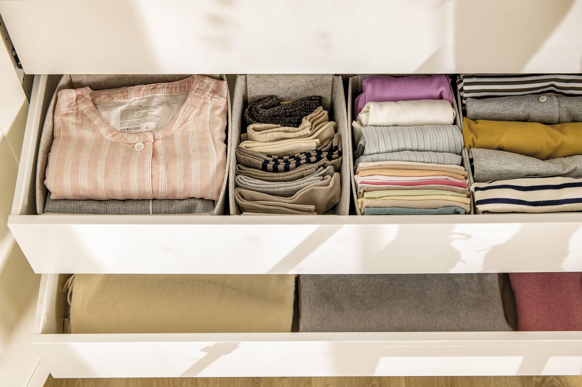 Cajones para la ropa organizados con cajas grises de IKEA.