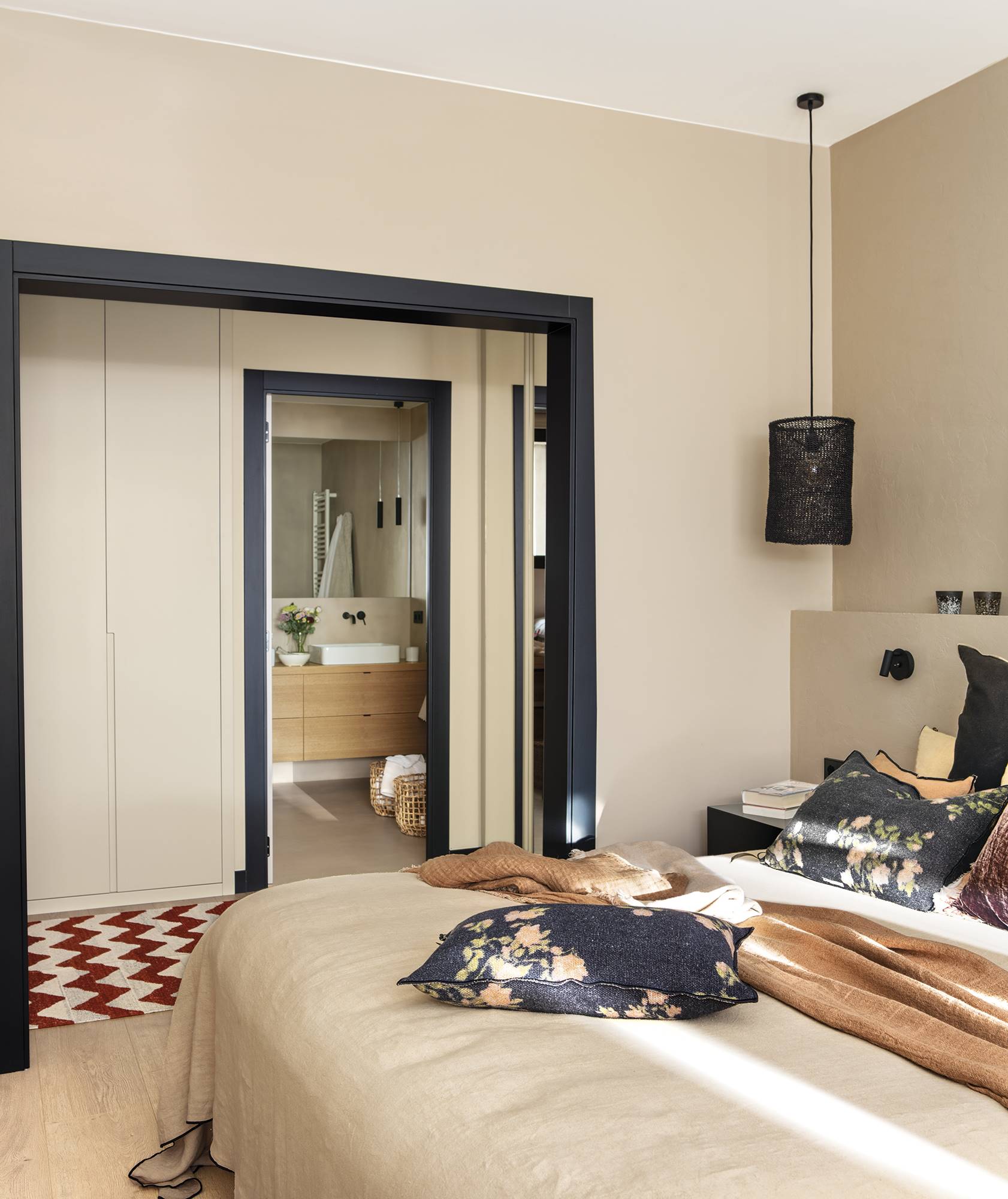 Dormitorio beige con carpintería negra y acceso al vestidor y el baño. 