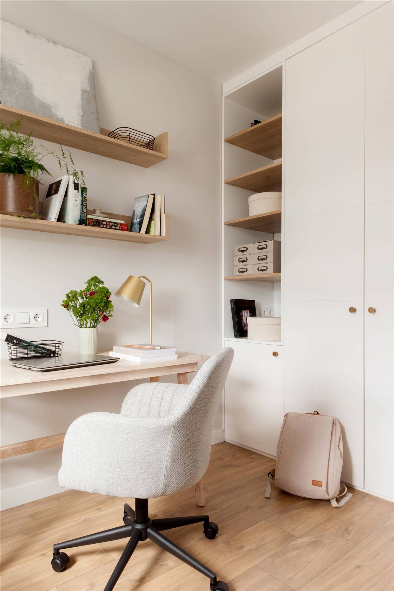 Un despacho lleno de estantes y armarios en madera y tonos blancos.