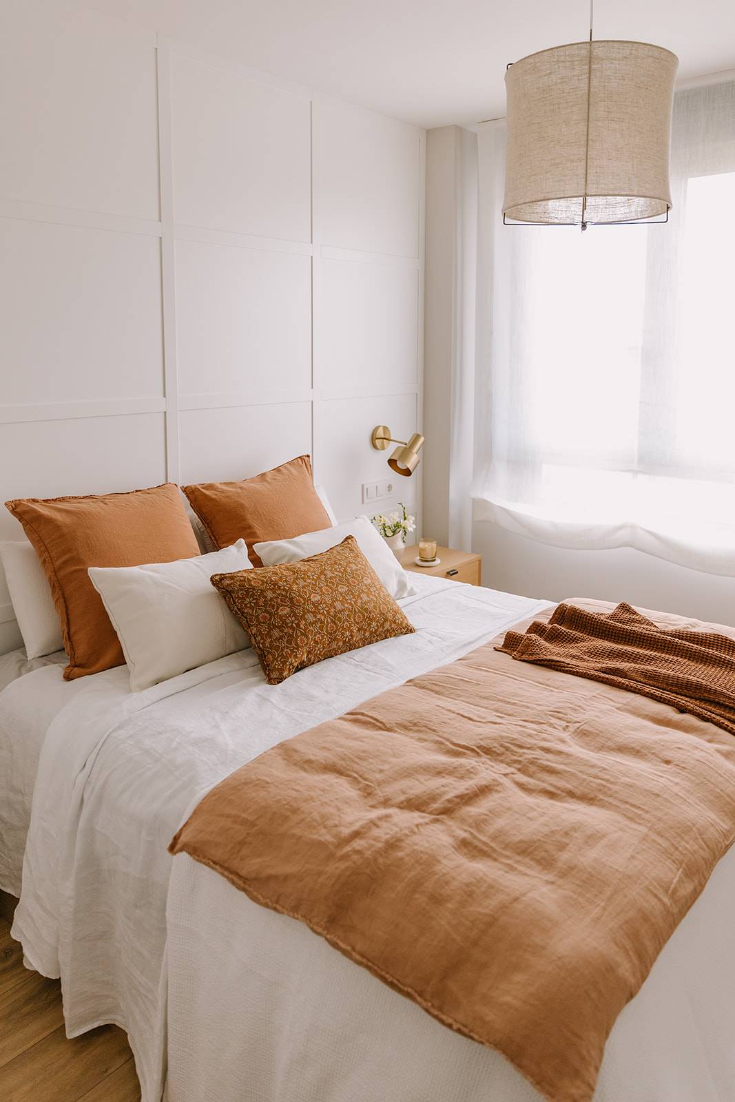 El dormitorio principal con textiles en tonos blancos y tejas.