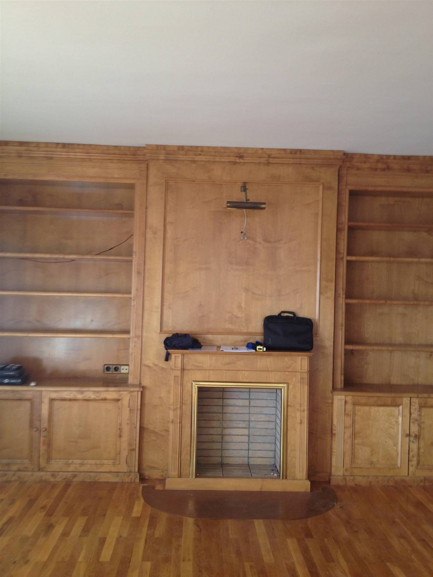 Librería de madera con molduras y chimenea sin pintar.