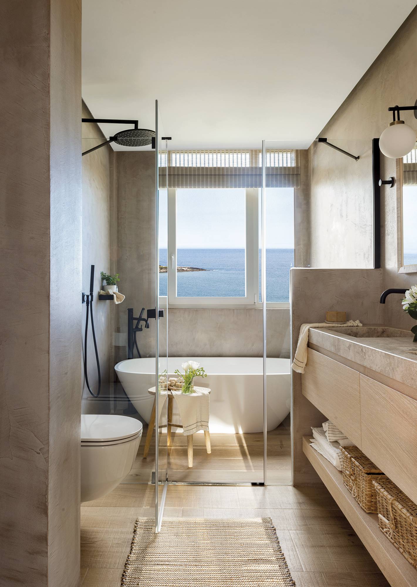 Baño moderno con una bañera exenta blanca y vistas al mar.