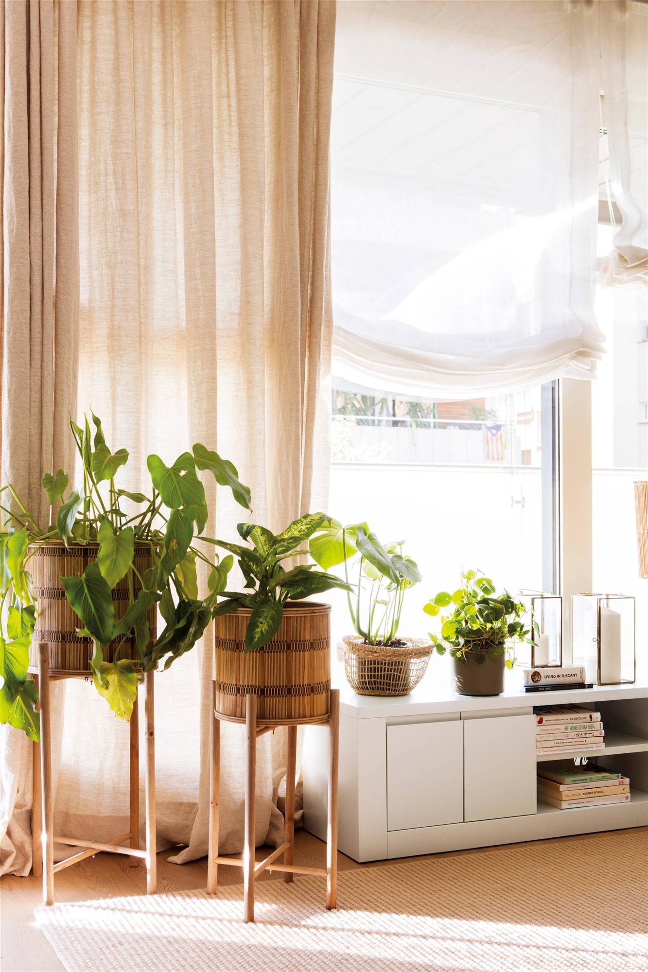 Plantas en maceteros altos y cortinas de lino que arrastran en color tostado.