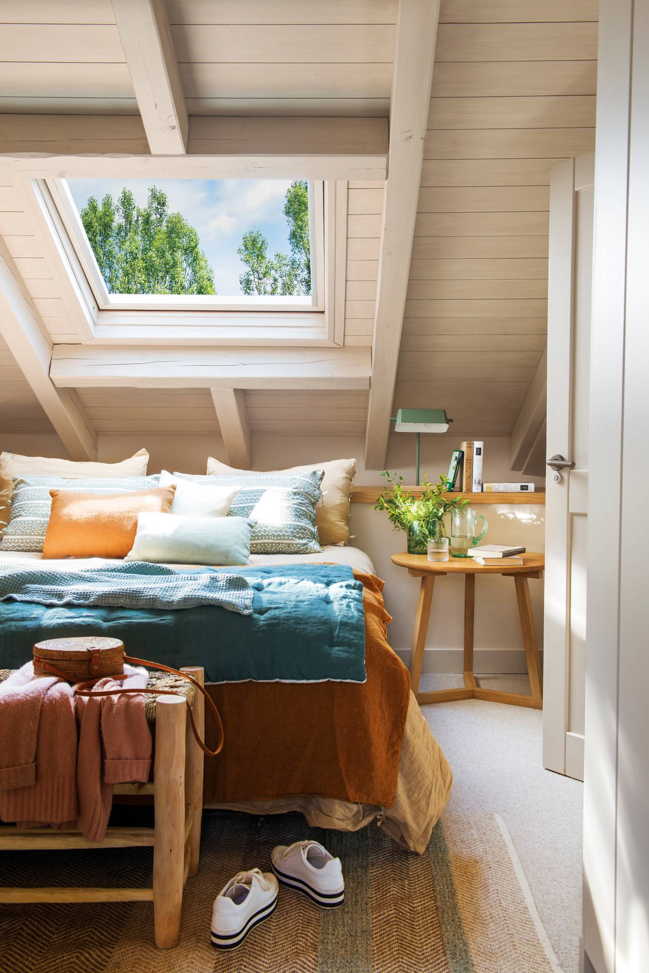 Dormitorio rústico con techo abuhardillado y ropa de cama azul. 