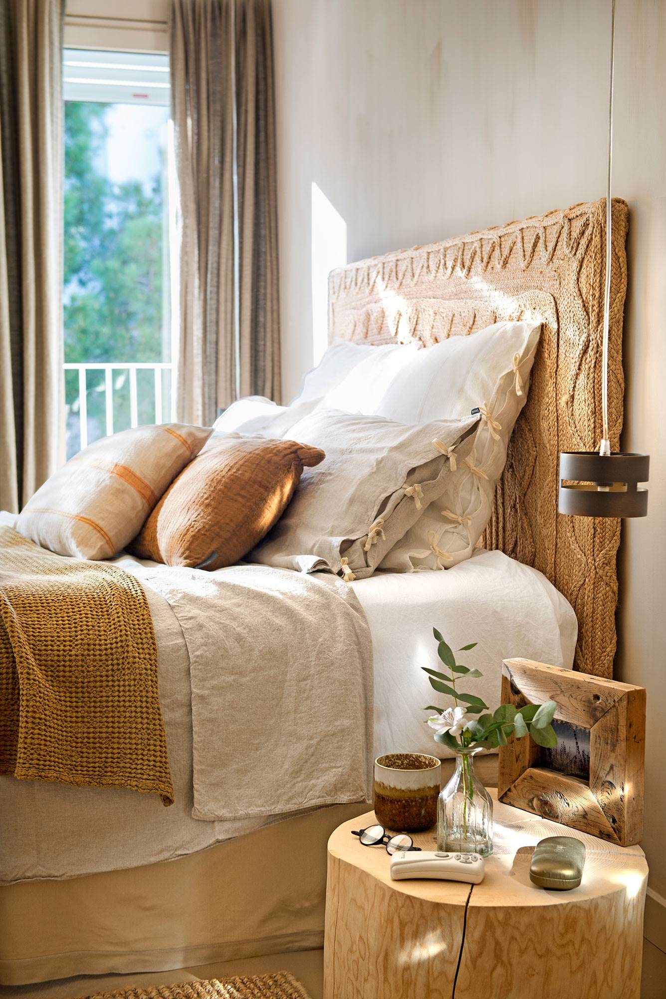 Dormitorio con cabecero de ratán diseñado por Julià Casals a partir de una alfombra de Zara Home.