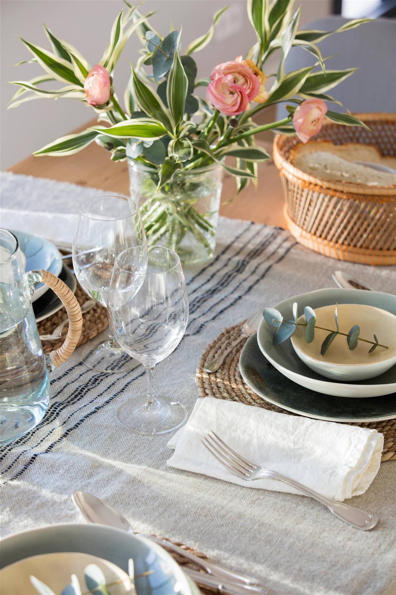 Detalle de mesa con mantel de lino, vajilla de cerámica e individual de fibra.