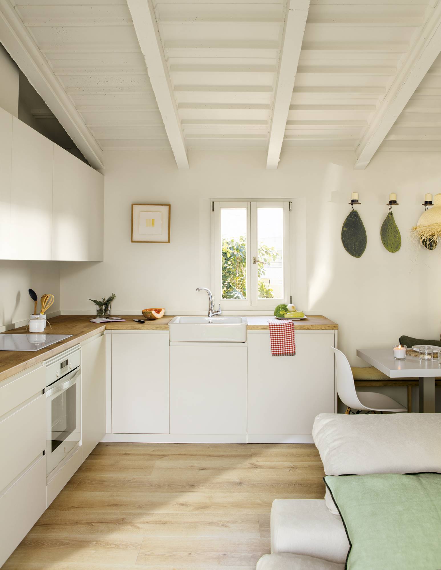 Cocina blanca con muebles blancos con frentes lisos y encimera de madera.  
